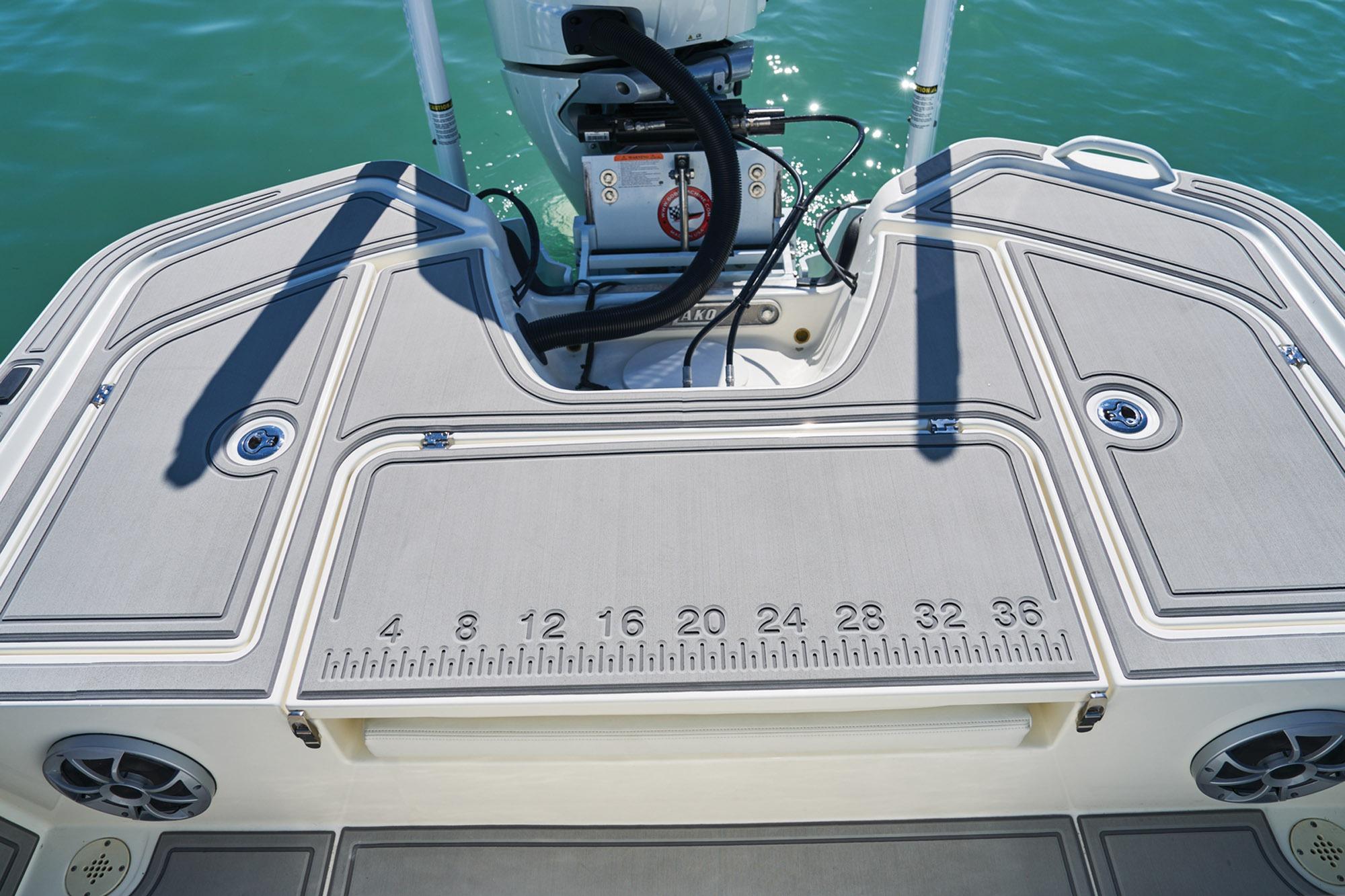 2026 Mako 24 APEX boat deck with ruler, motor, and storage compartments.