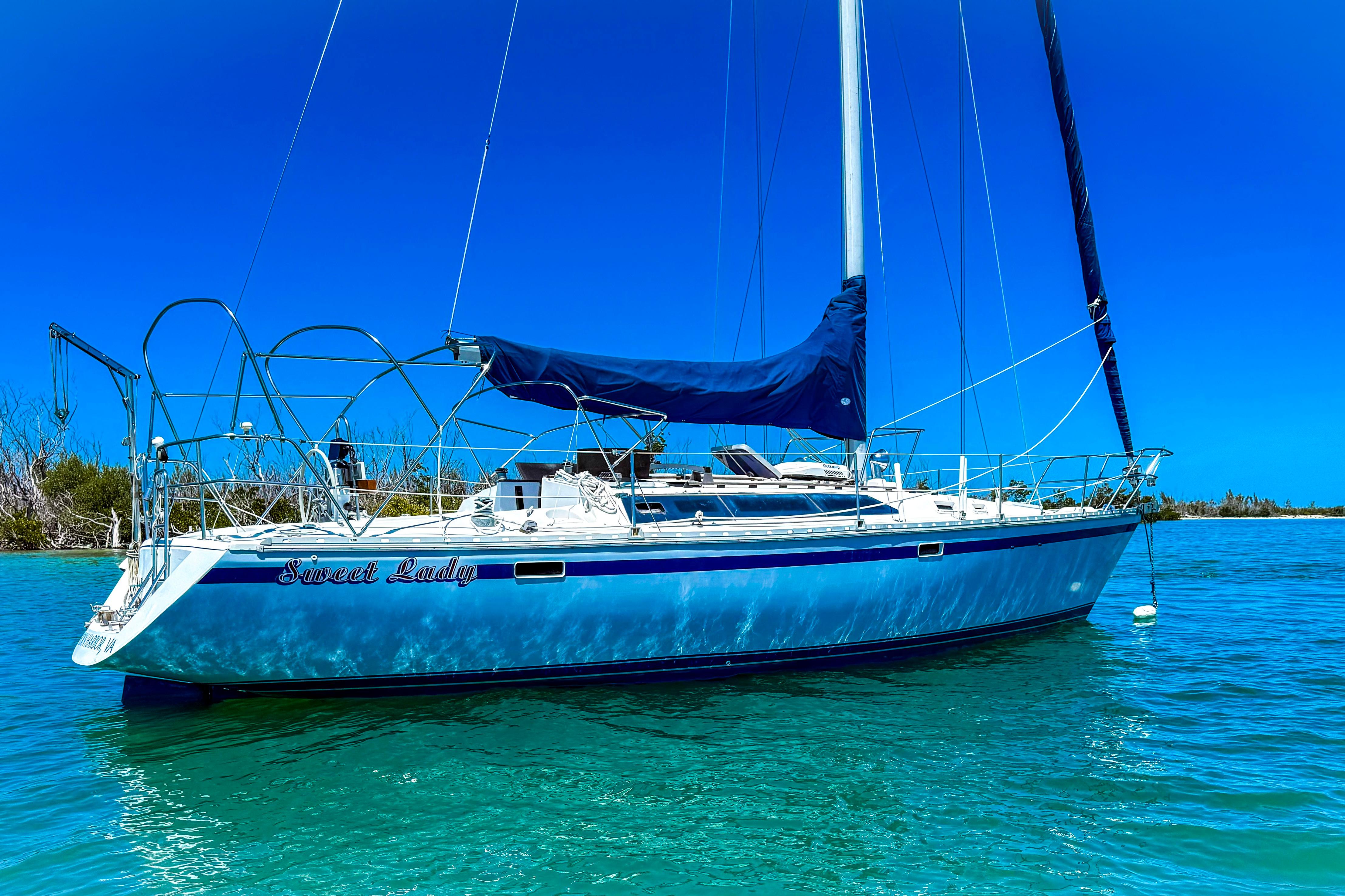 1988 Oday 40 sailboat "Sweet Lady" anchored in clear turquoise waters under a bright blue sky.