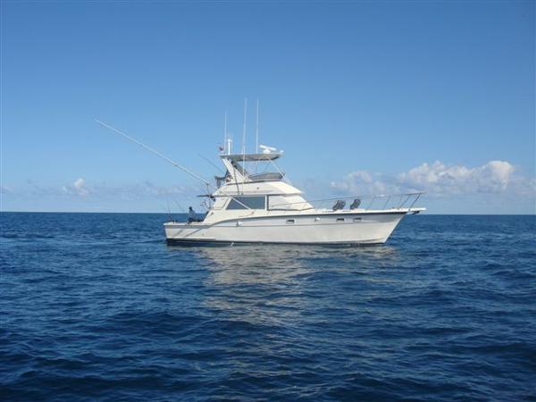1985 Hatteras 45 Convertible yacht on open sea under clear blue sky.