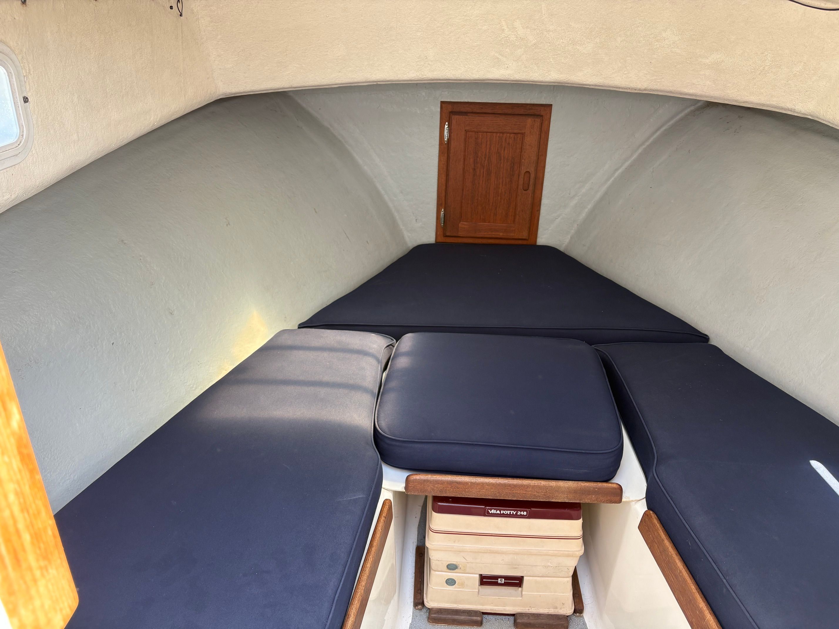 The image shows the interior of a 1990 Portsmouth 22 boat with blue cushions.