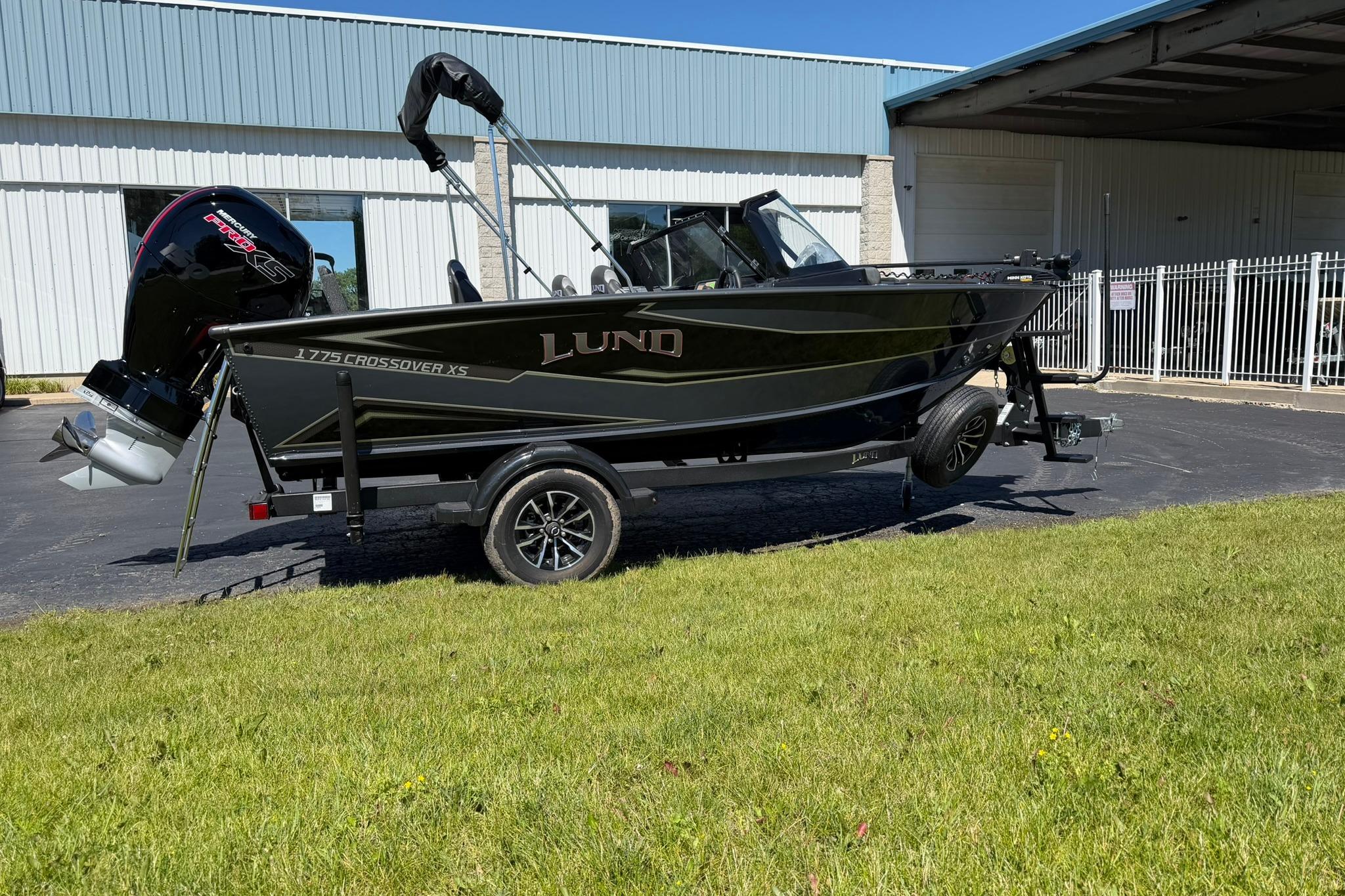 2027 Lund 1775 Crossover XS boat on trailer, parked outdoors near a building.