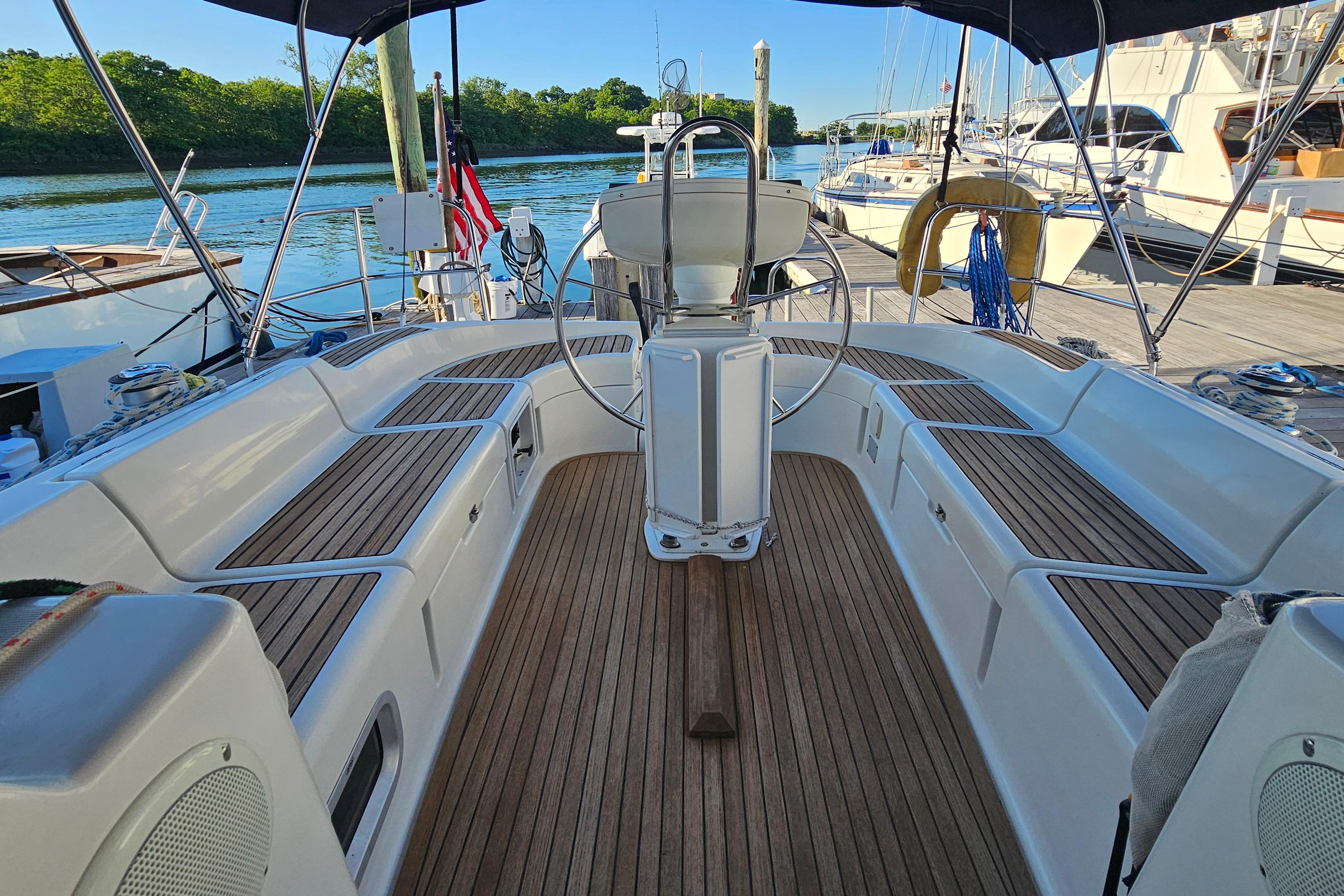 Cockpit of 2002 Jeanneau Sun Odyssey 37 sailboat with wooden seating and steering wheel.