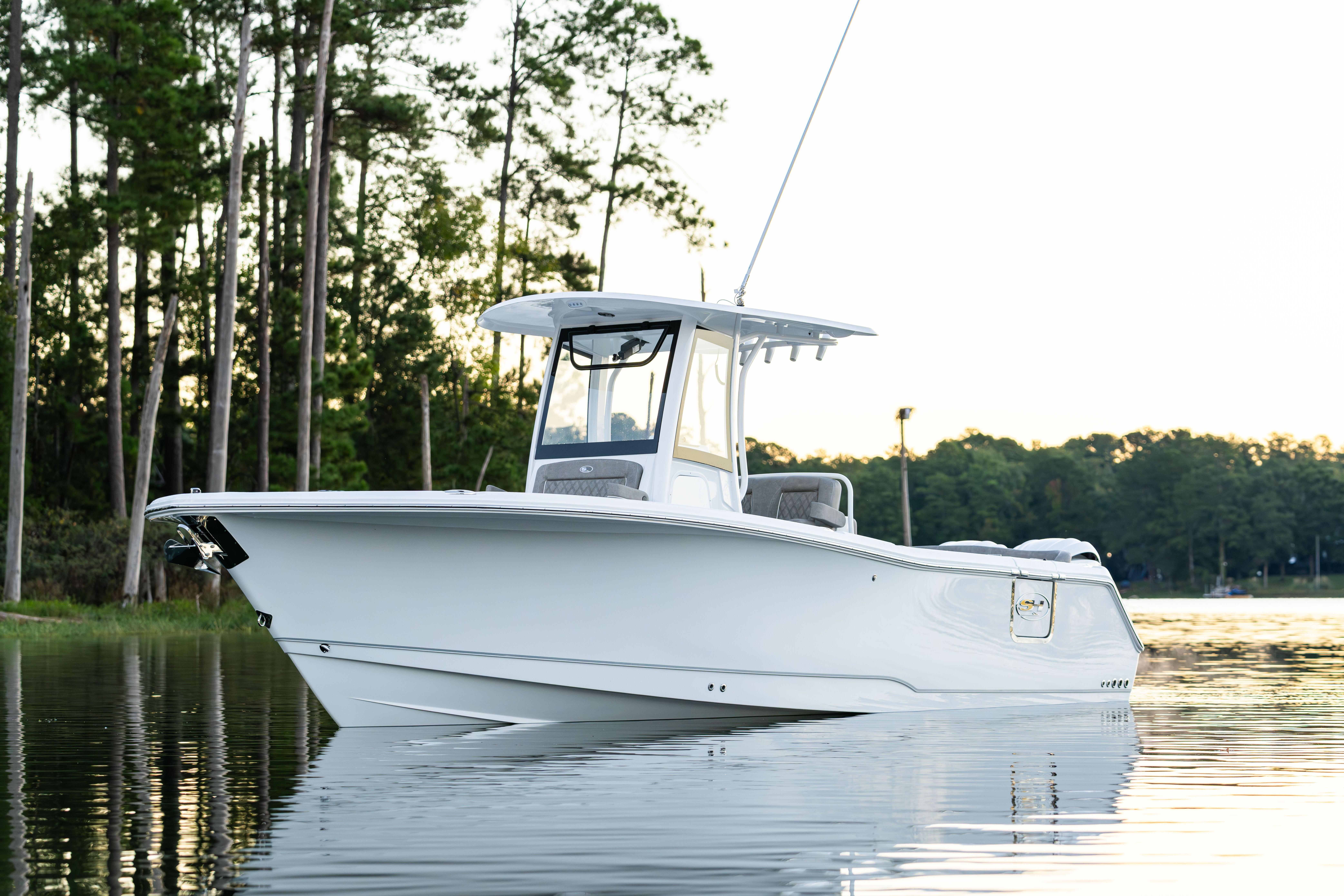 2026 Sea Hunt Ultra 275 Coffin Box boat on calm water, surrounded by trees.