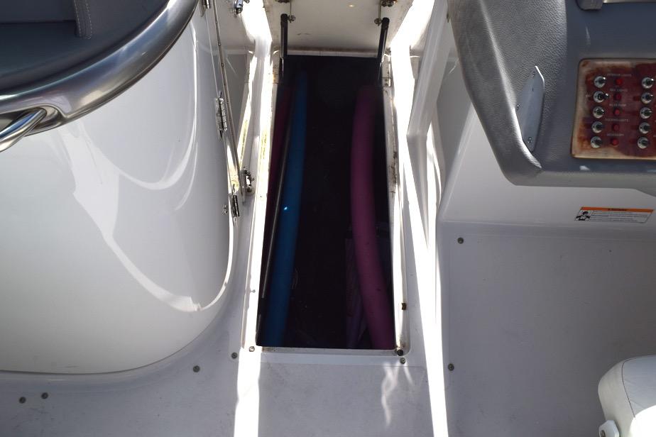 Storage compartment on a 2006 Cobalt 240 boat with visible pool noodles.