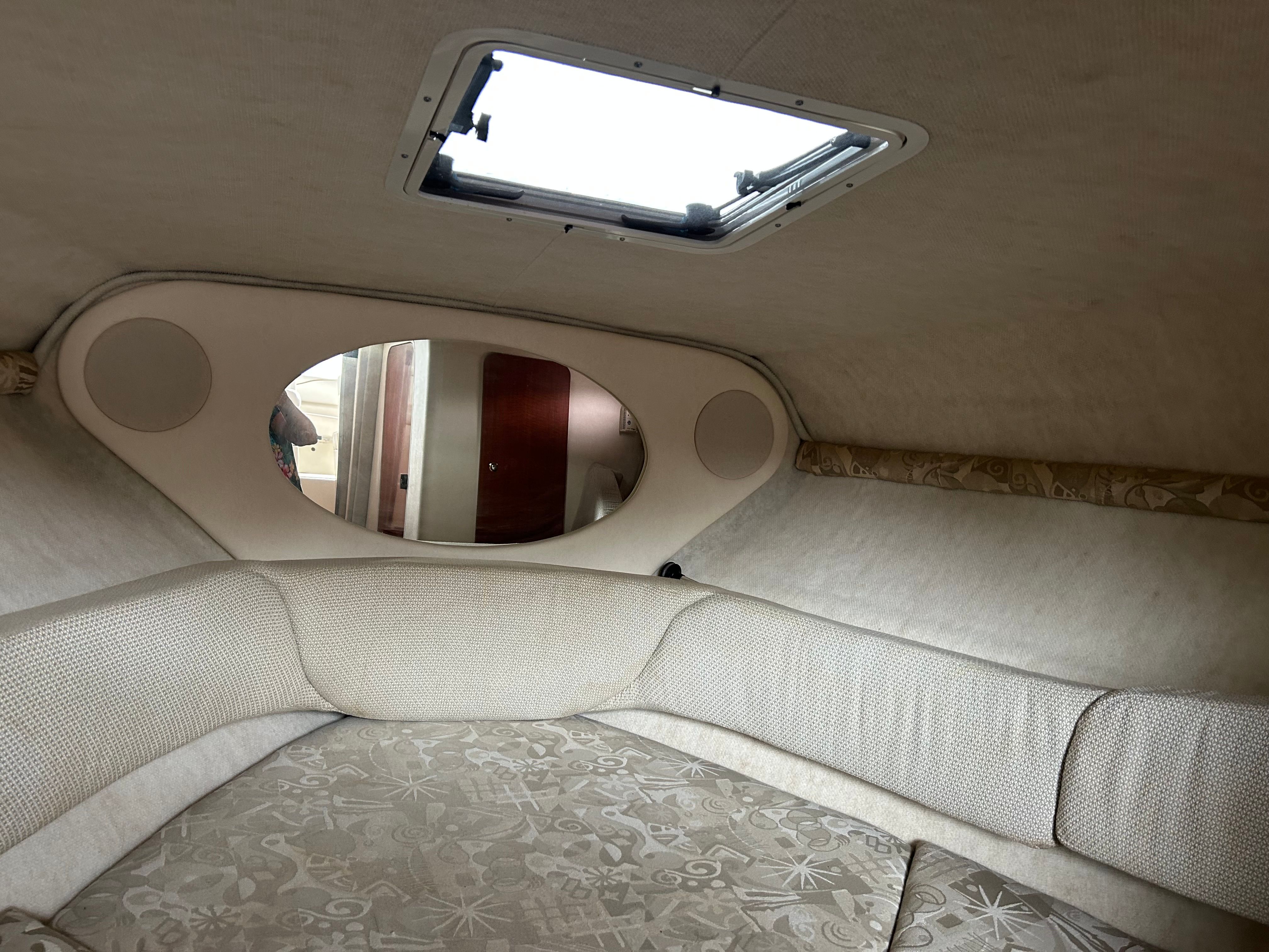 Interior cabin of 2003 Sea Ray 240 Sundancer with cushioned seating and overhead hatch.