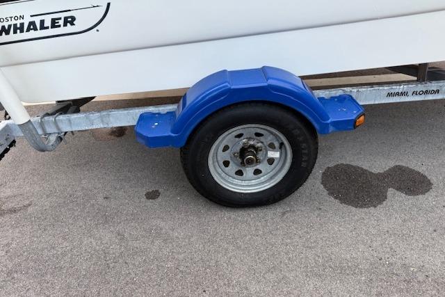 Trailer wheel of a 2016 Boston Whaler 150 Montauk, parked on pavement.