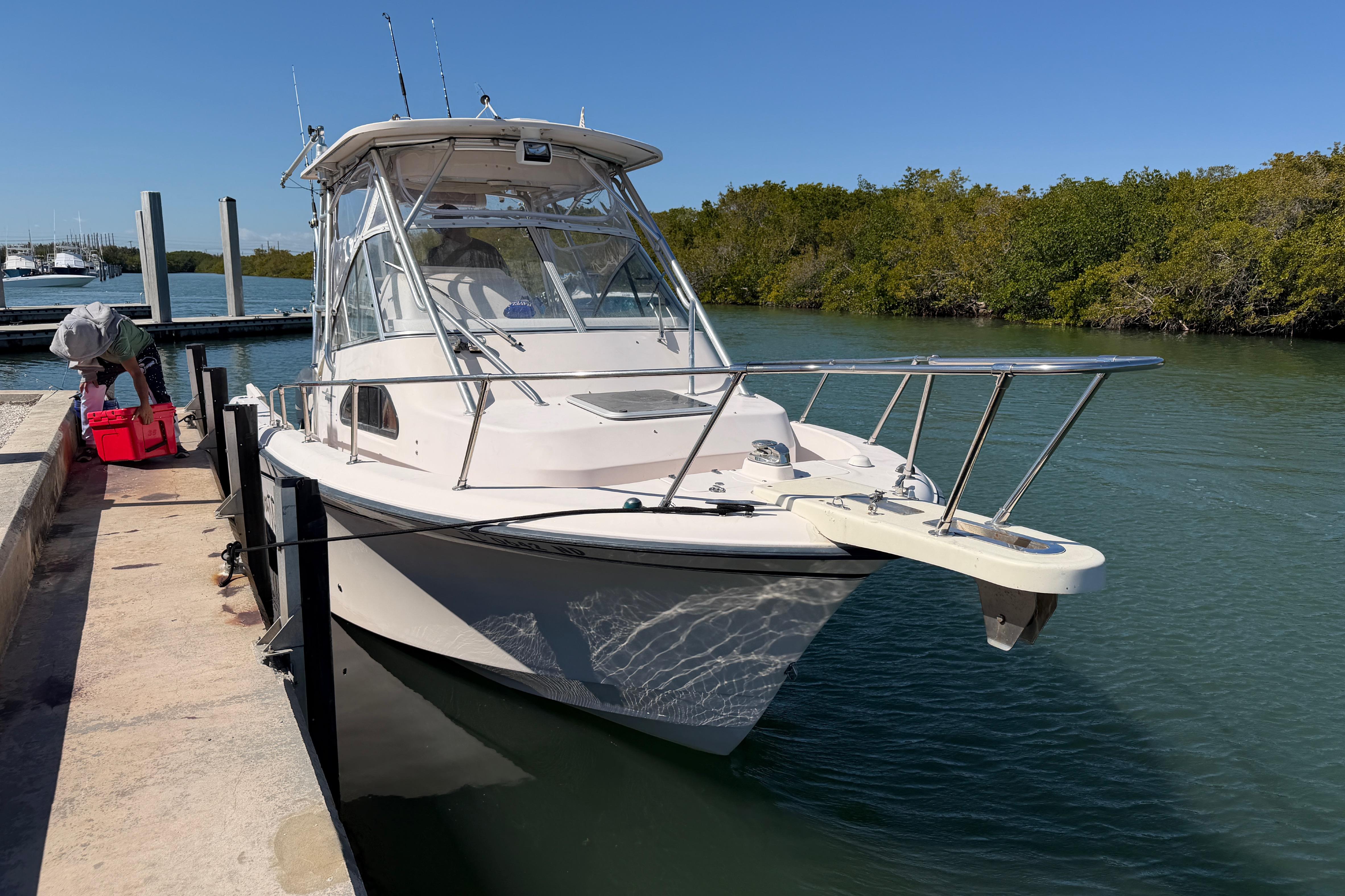 2006 Grady-White Sailfish 282 docked by a serene waterway with lush greenery.