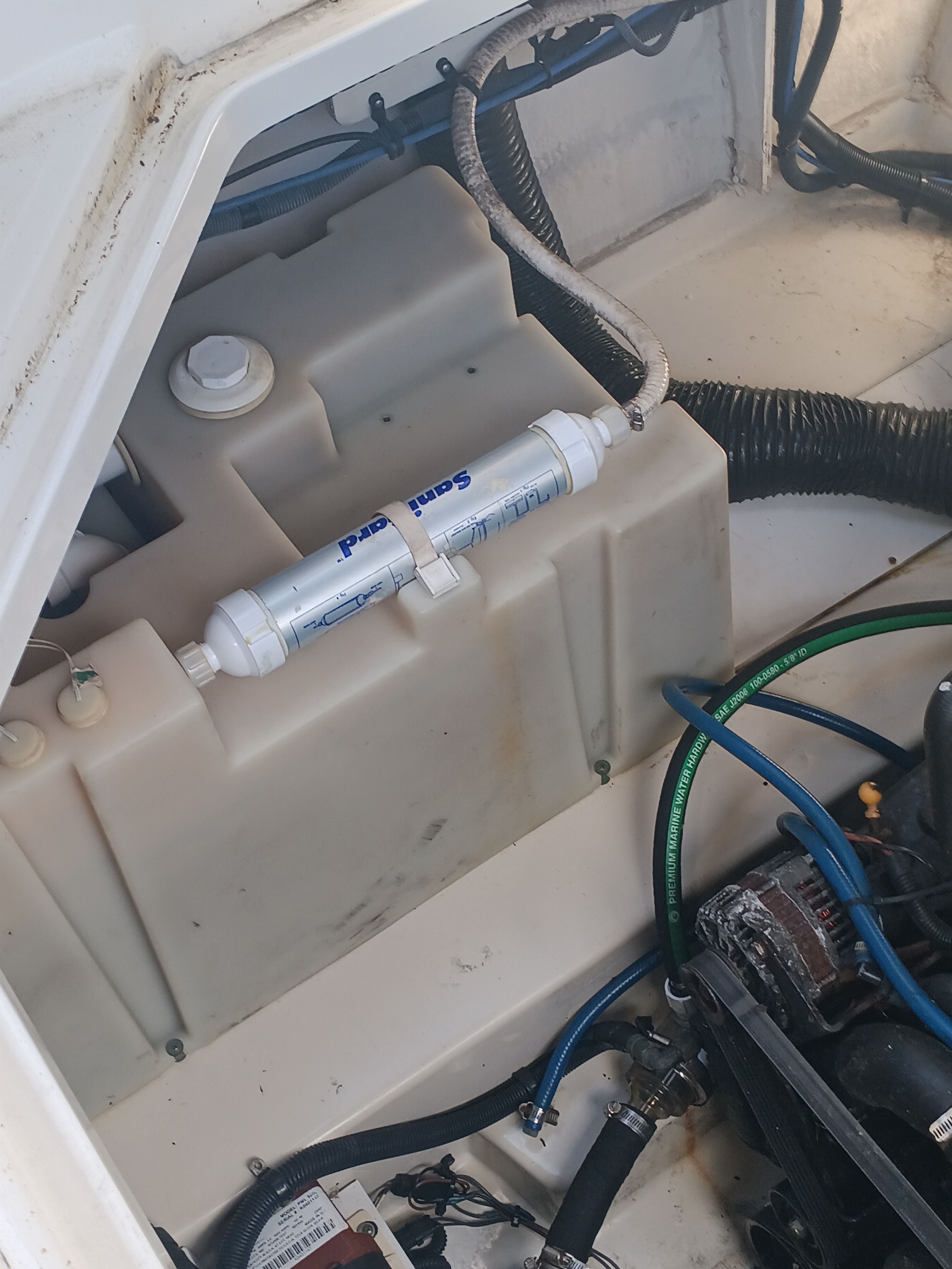 A view of the engine compartment of a 2005 Sea Ray 260 DA Sundancer with hoses and a filter.