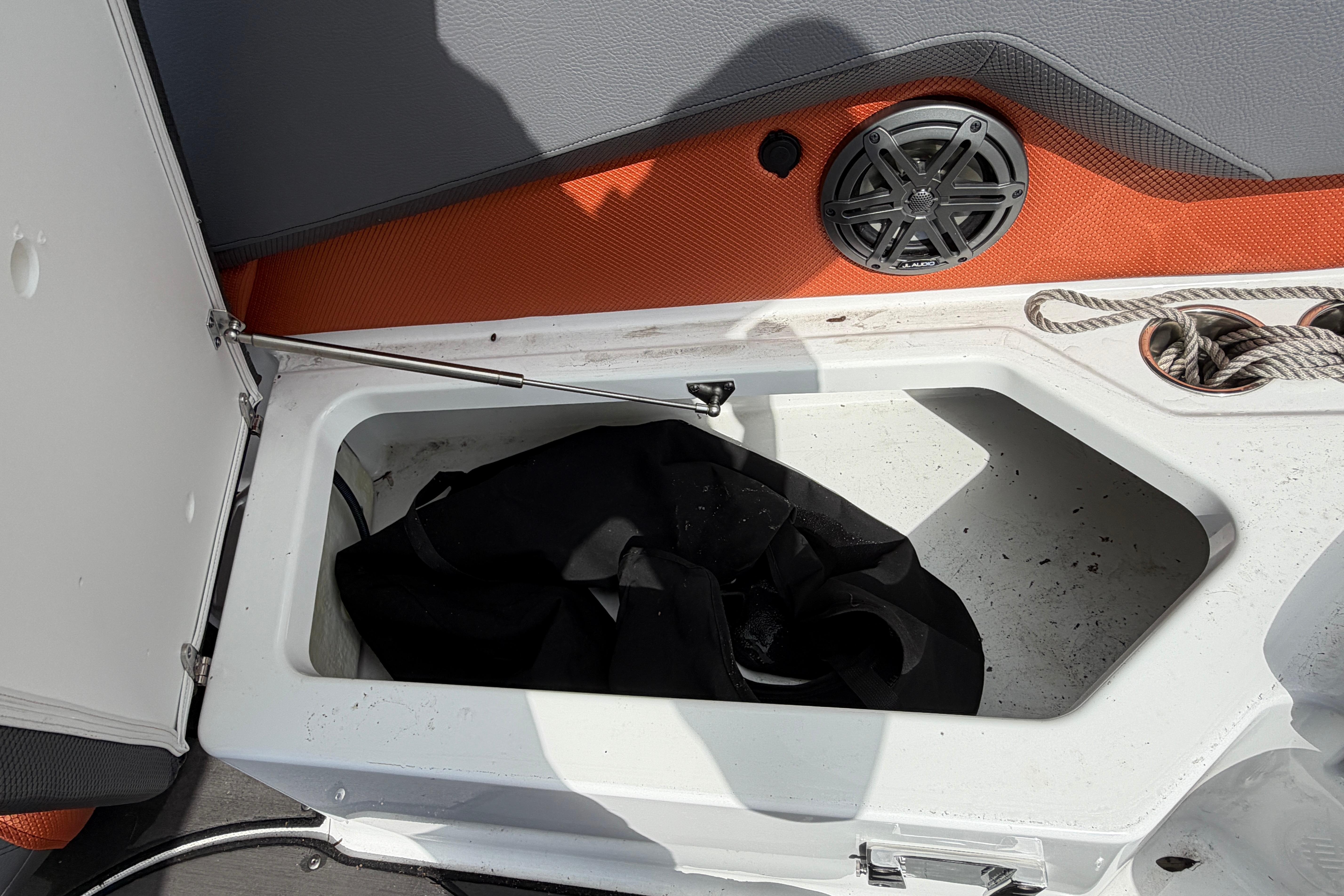 Storage compartment in 2026 Scarab 235 LX boat with speaker and rope.