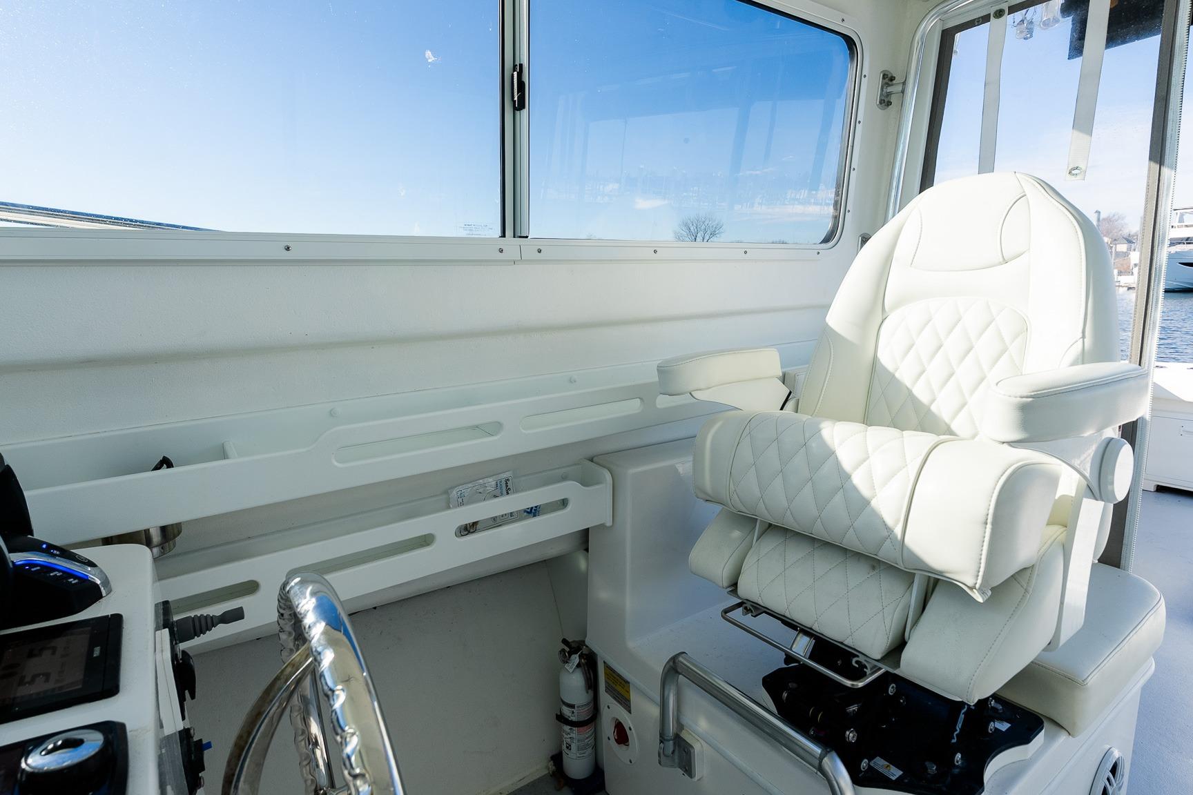 2024 Steiger Craft 31 Fisherman helm with luxurious white captain's chair and steering wheel.