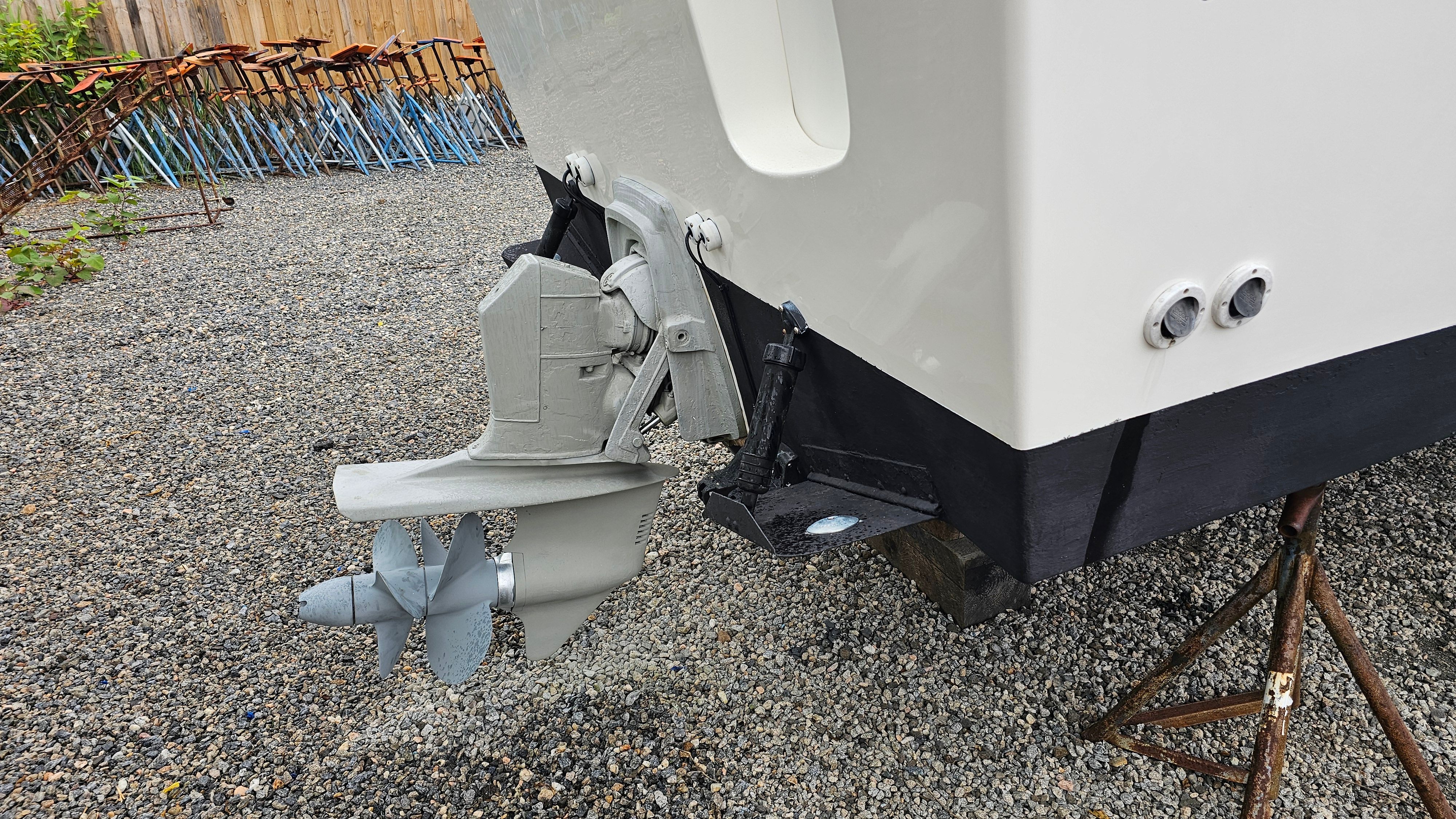 Osprey 26 EXPEDITION 2004 boat hull with outboard motor on gravel.