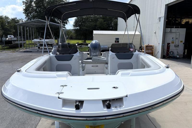 2026 Hurricane SunDeck Sport 2050 OB boat with canopy, docked outdoors.