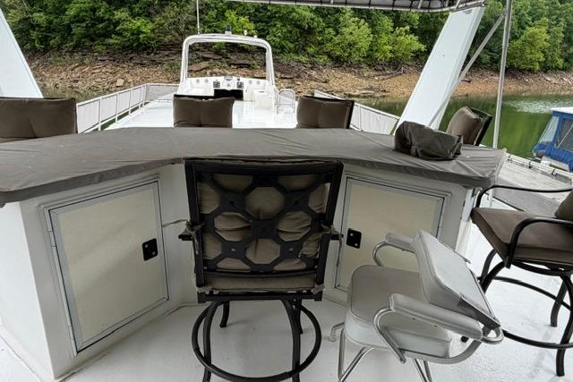 Outdoor seating area on 1997 Stardust Houseboat 18x83, featuring bar stools and scenic lake view.
