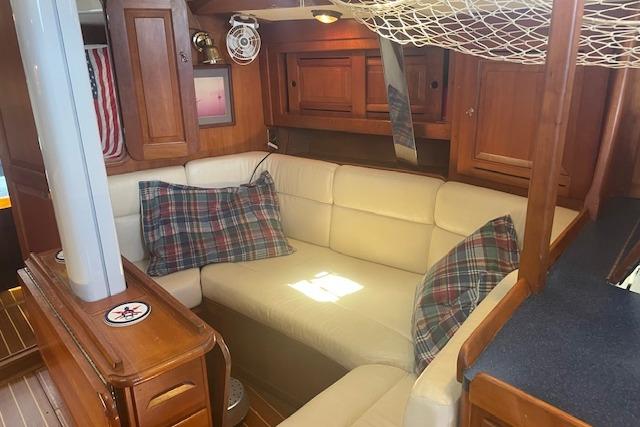 Cozy interior of 2001 Tartan 3700 sailboat with plaid pillows and wooden cabinetry.