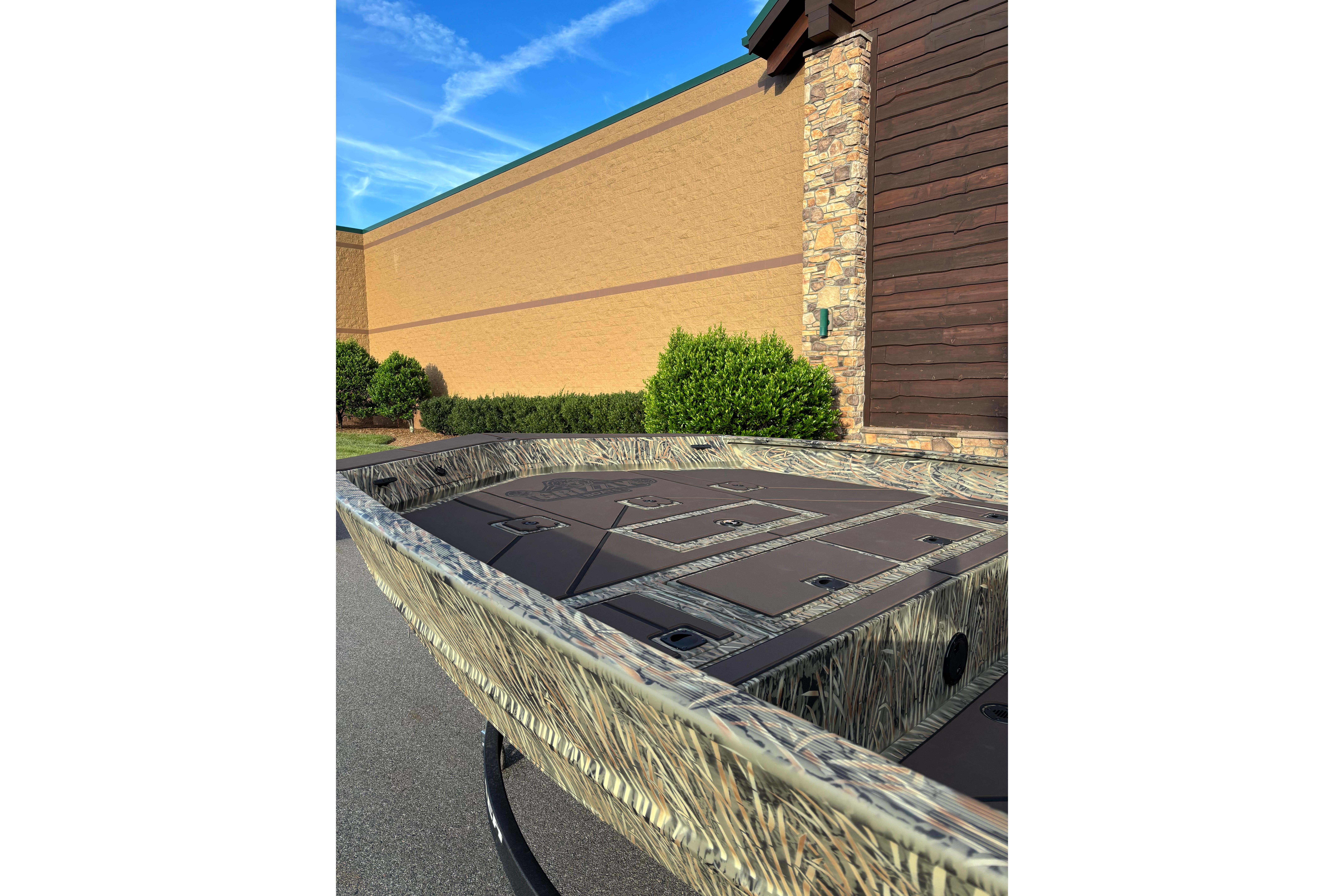 2026 Tracker Grizzly 2072 CC boat with camouflage design, parked outdoors near a building.