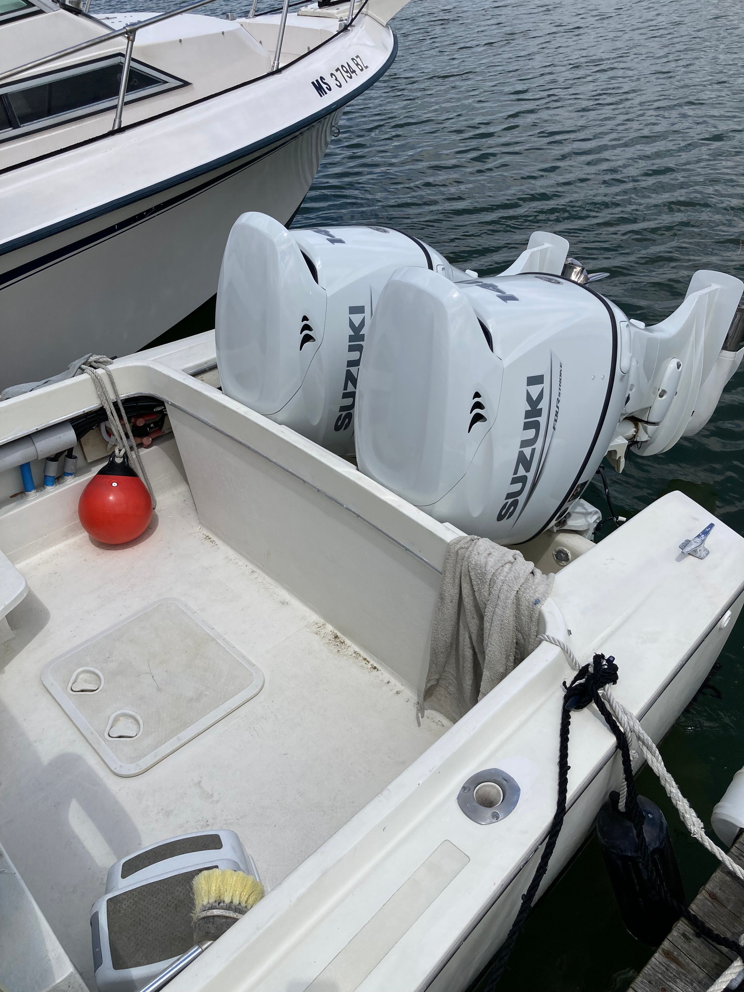 A 1969 Bertram Bahia Mar with two Suzuki outboard engines at the dock.