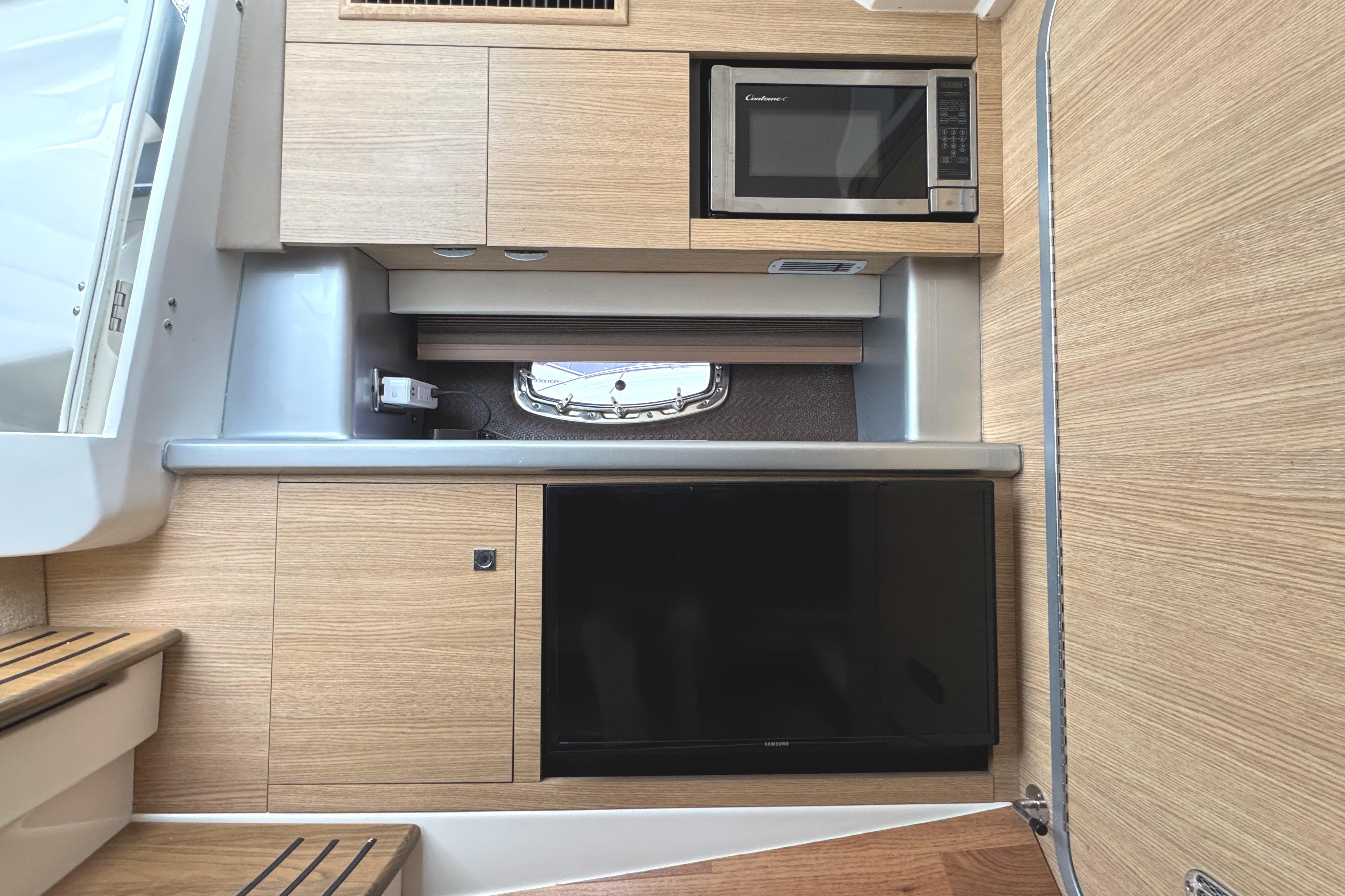 2012 Chaparral 327 SSX interior with microwave and TV in modern wood finish.