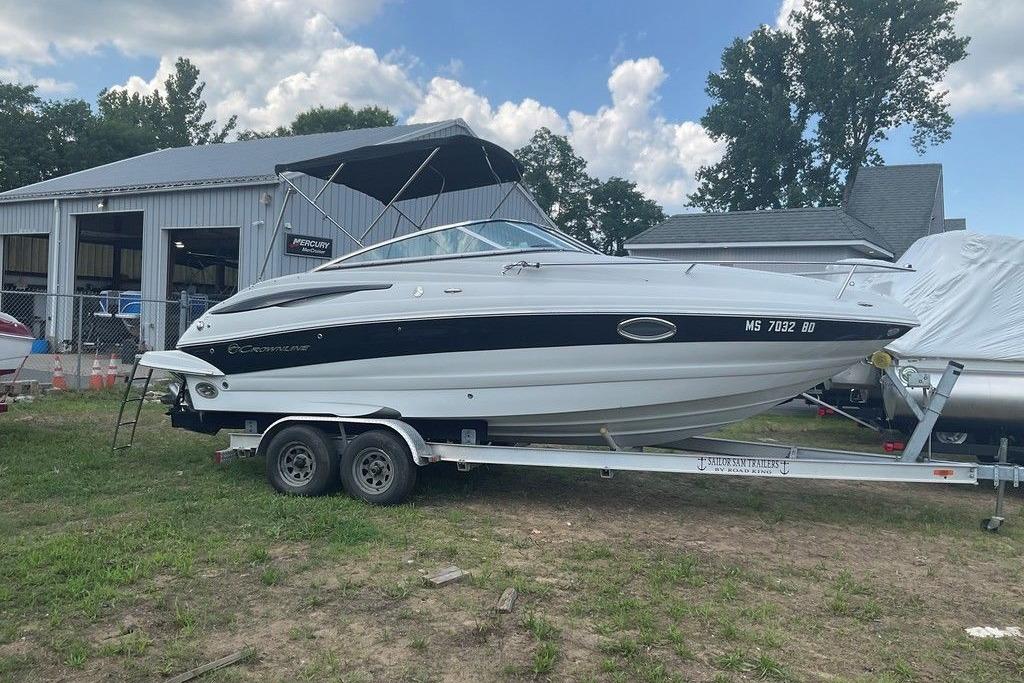 2015 Crownline 236 SC boat on trailer near a garage, under a partly cloudy sky.