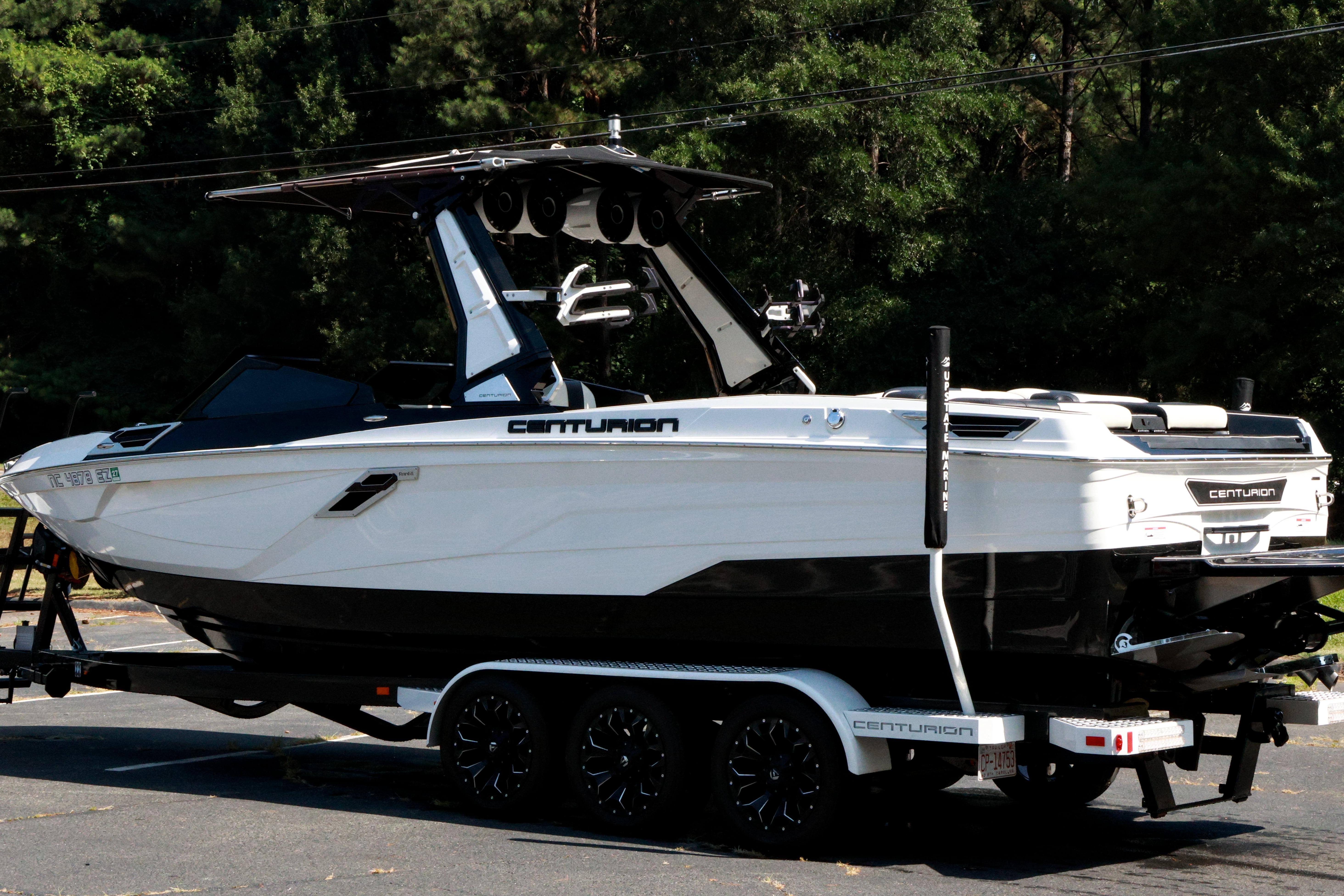 2022 Centurion Ri265 boat on trailer, parked outdoors with lush greenery background.