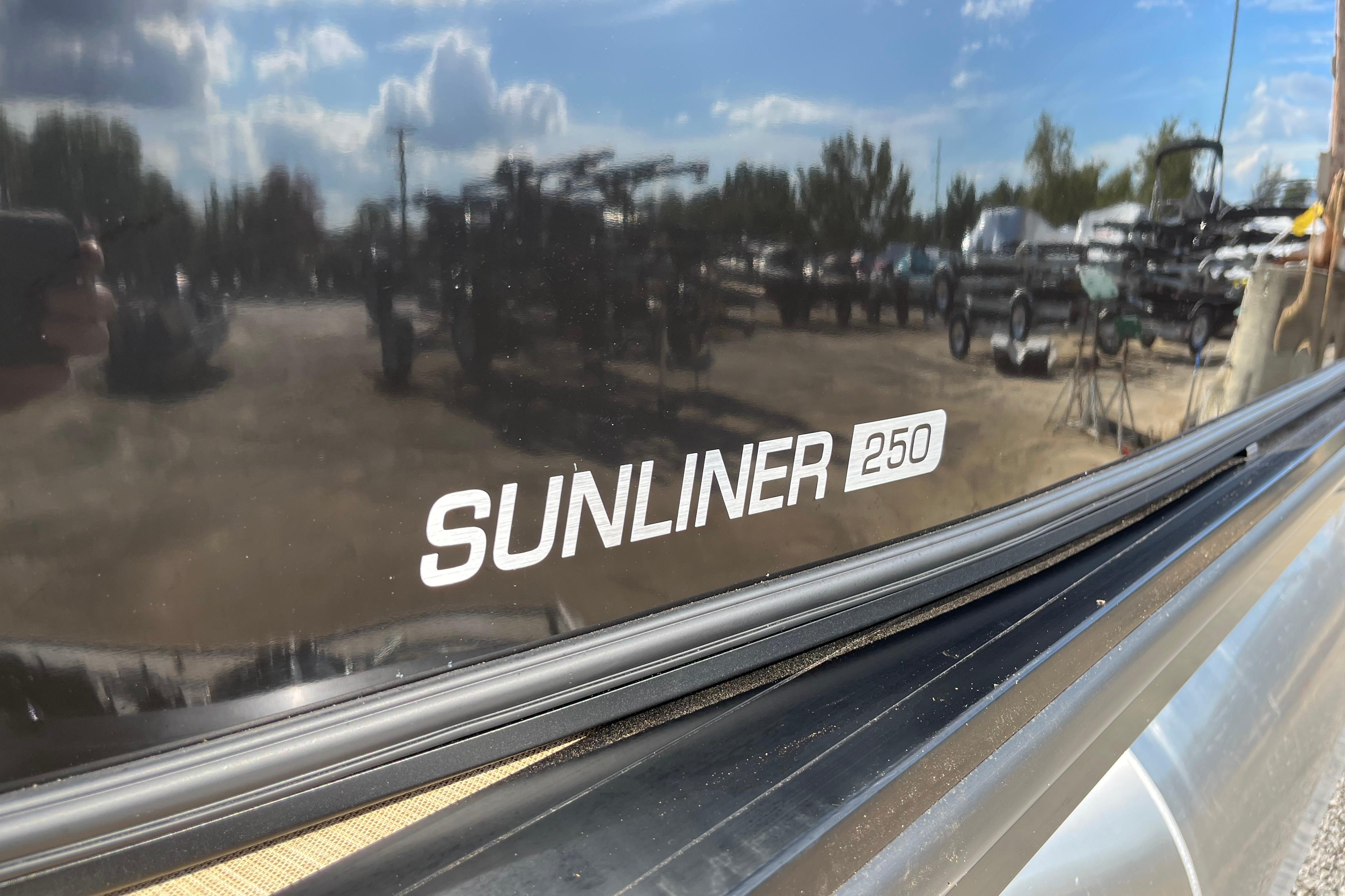 2025 Harris Sunliner 250 boat with reflective surface and outdoor background.