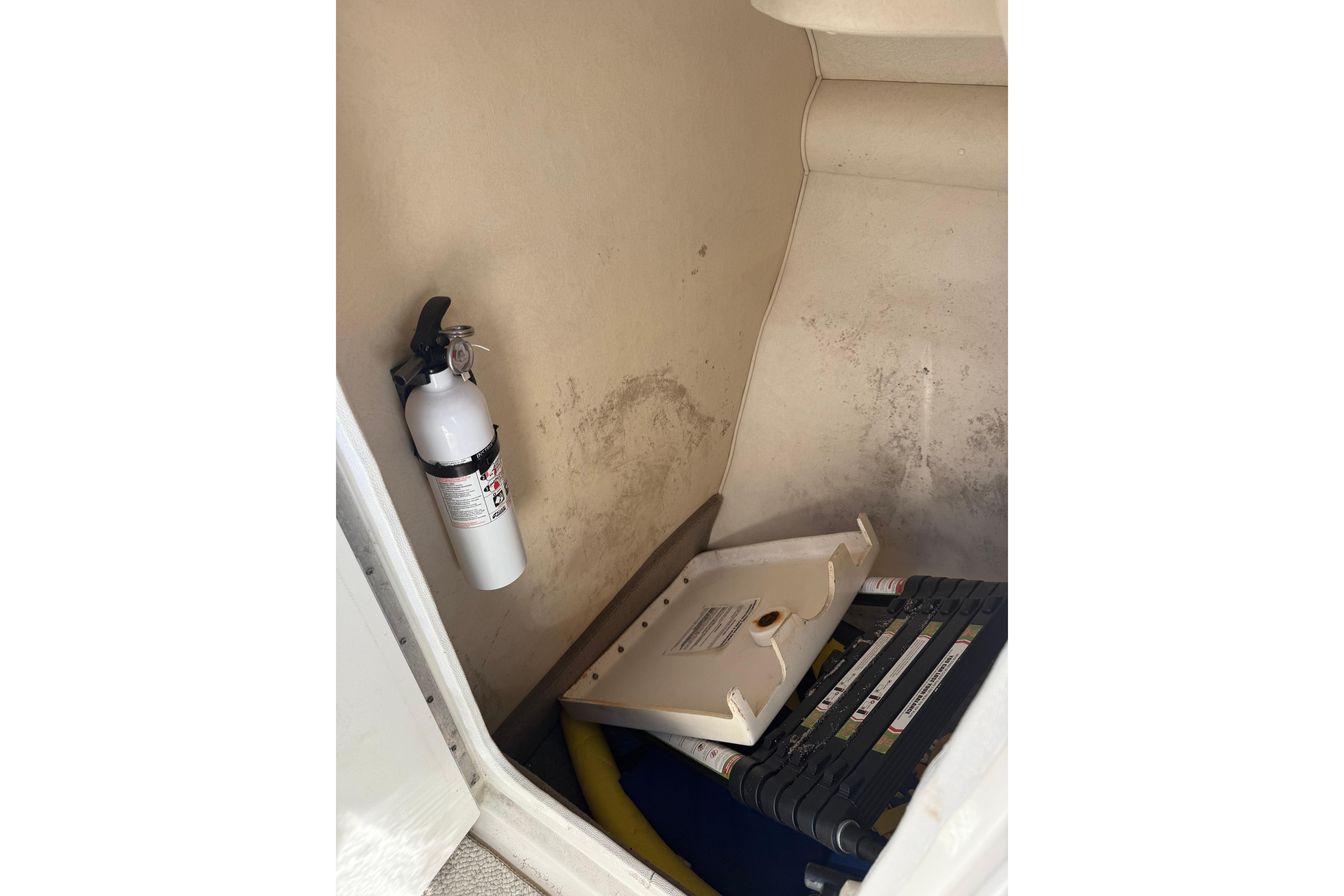 Storage compartment in a 2005 Sea Ray 290 SLX with fire extinguisher and equipment.