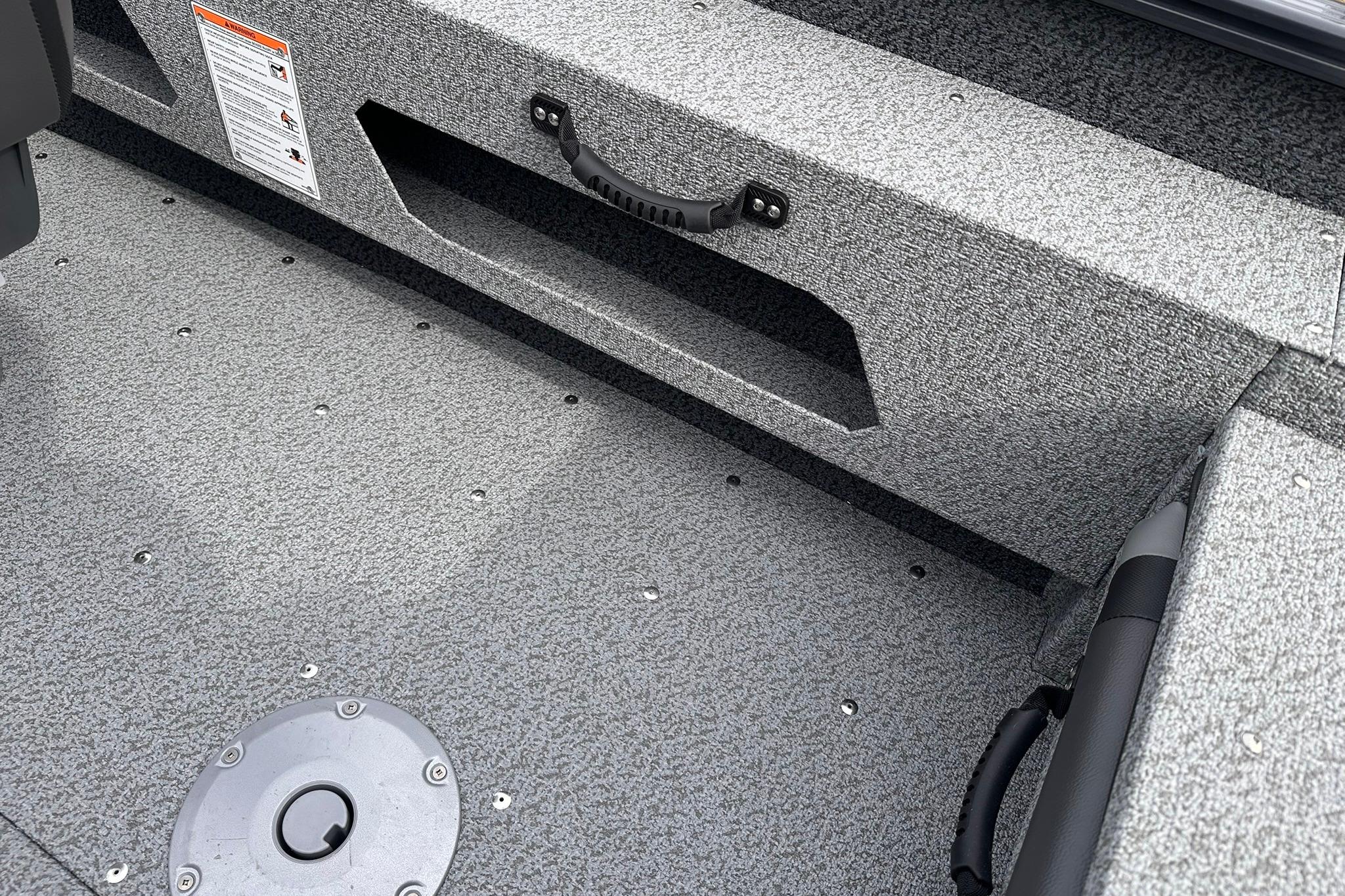 Interior of 2026 Lund 1775 Adventure Sport boat, featuring textured flooring and storage compartment.