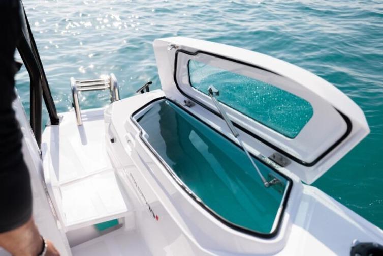 2027 Axopar 29 CCX boat with open storage compartment on clear blue water.