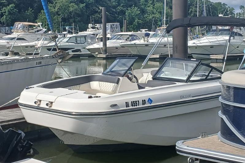 2023 Bayliner DX 2200 boat docked at a marina with other vessels.