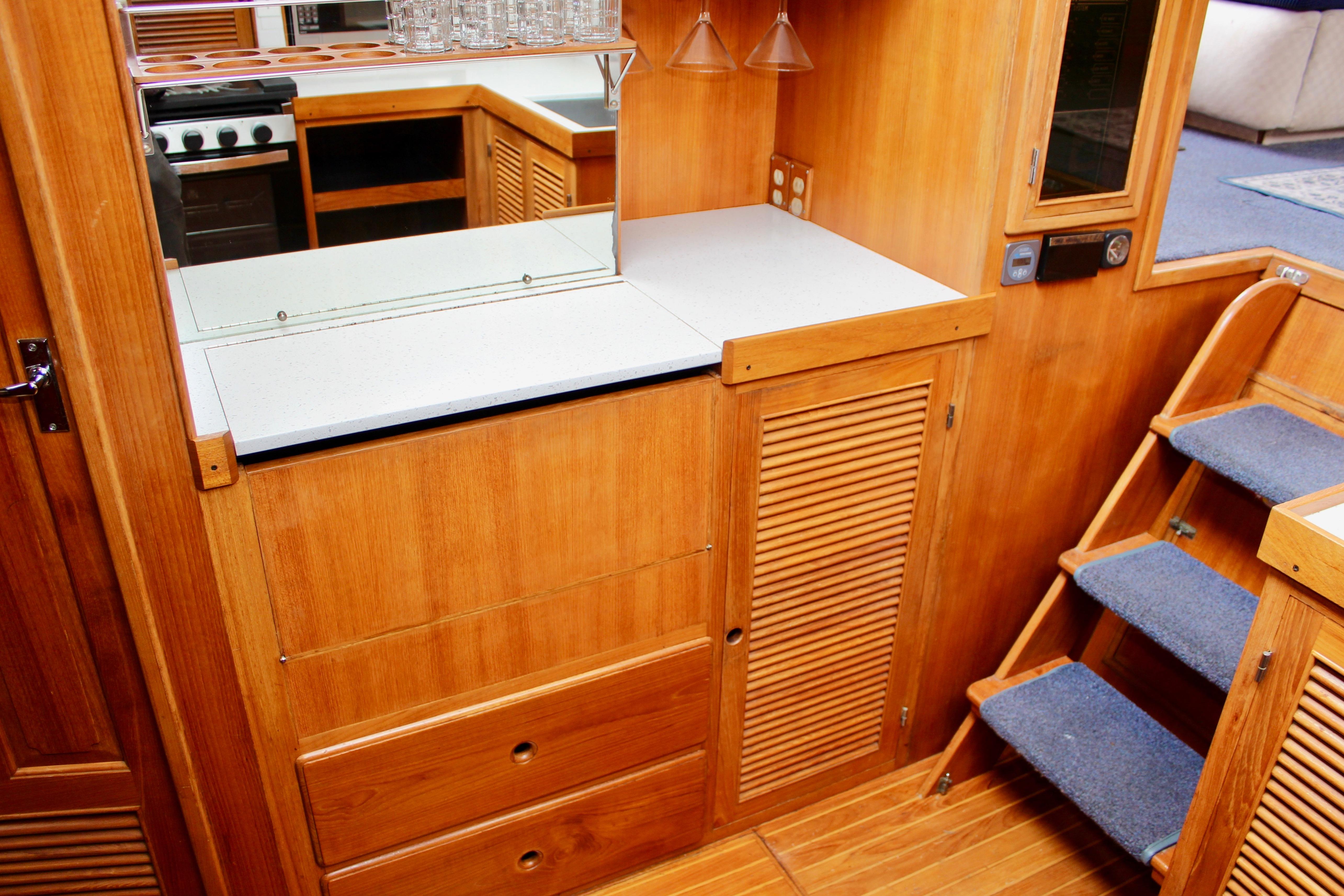 Interior of 1986 Kha Shing Spindrift 46 yacht with wooden cabinetry and carpeted stairs.