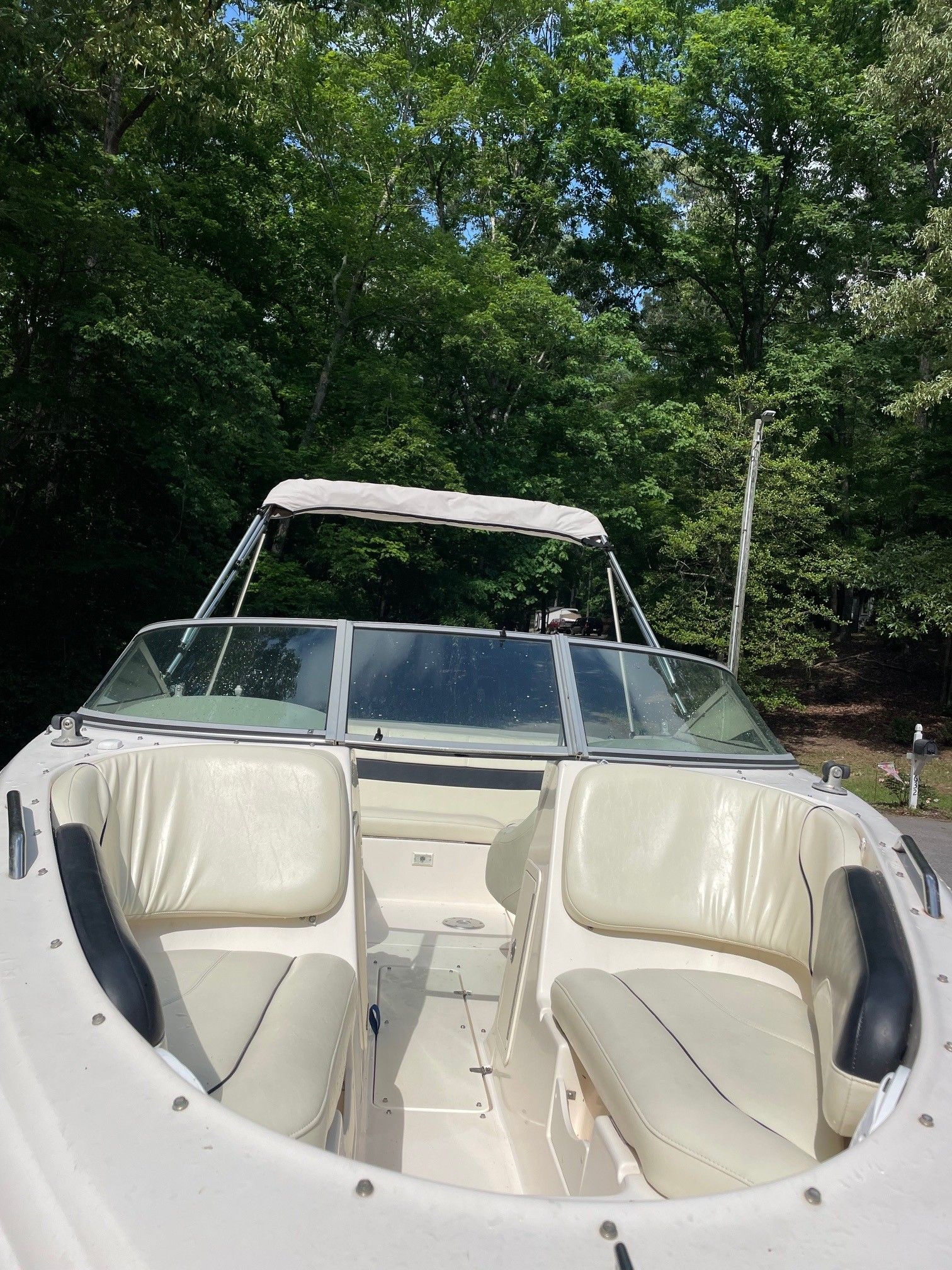 2002 Rinker 212 Captiva Bowrider with white leather seats in a forest setting.