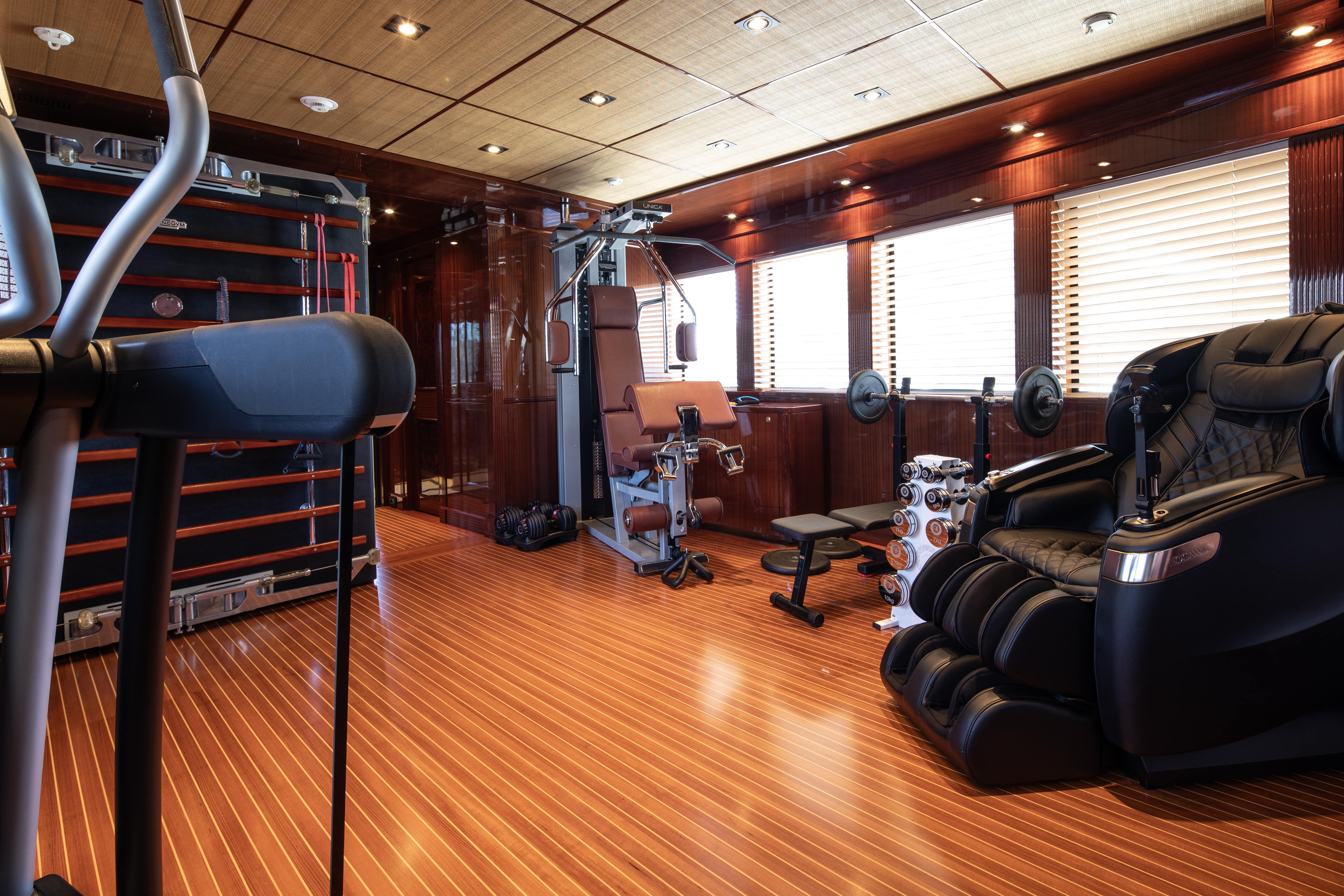 Luxurious yacht gym with modern equipment, wood flooring, and massage chair, CRN 185, 2008 model.