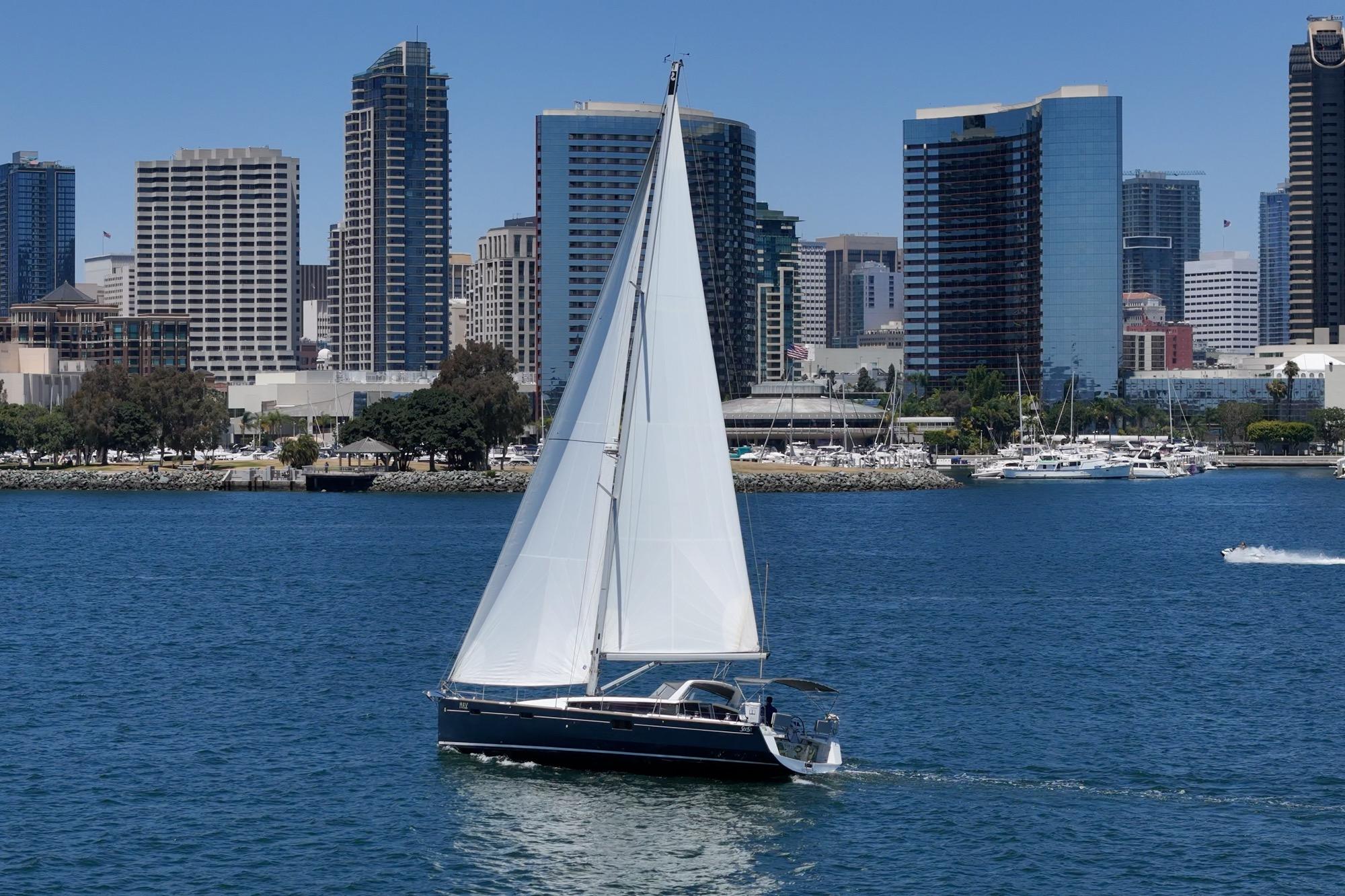 Sailing yacht Beneteau Sense 50, 2017, cruising near city skyline on a sunny day.