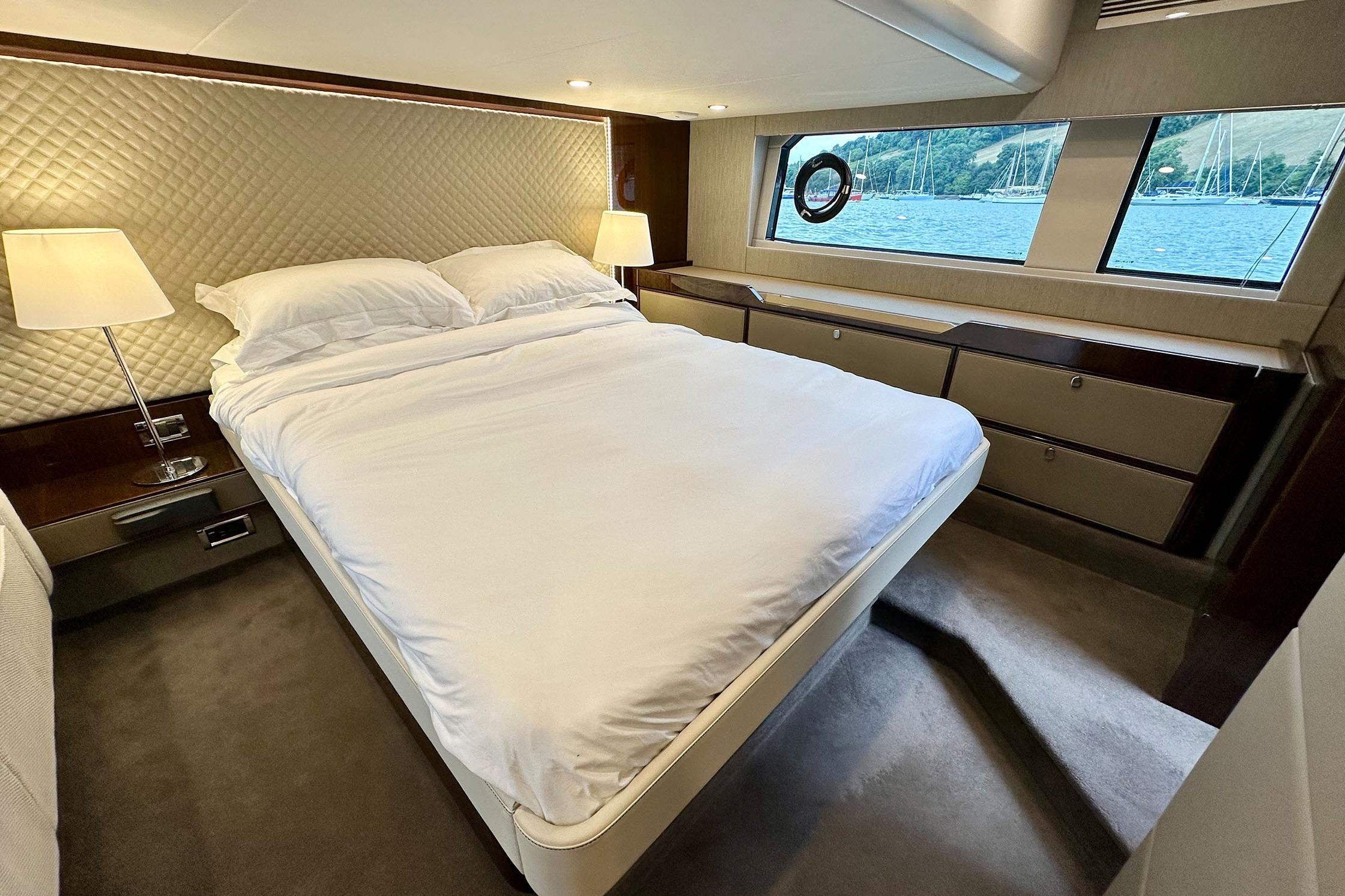 Luxurious bedroom interior of 2022 Fairline Targa 50 GT yacht with scenic window view.