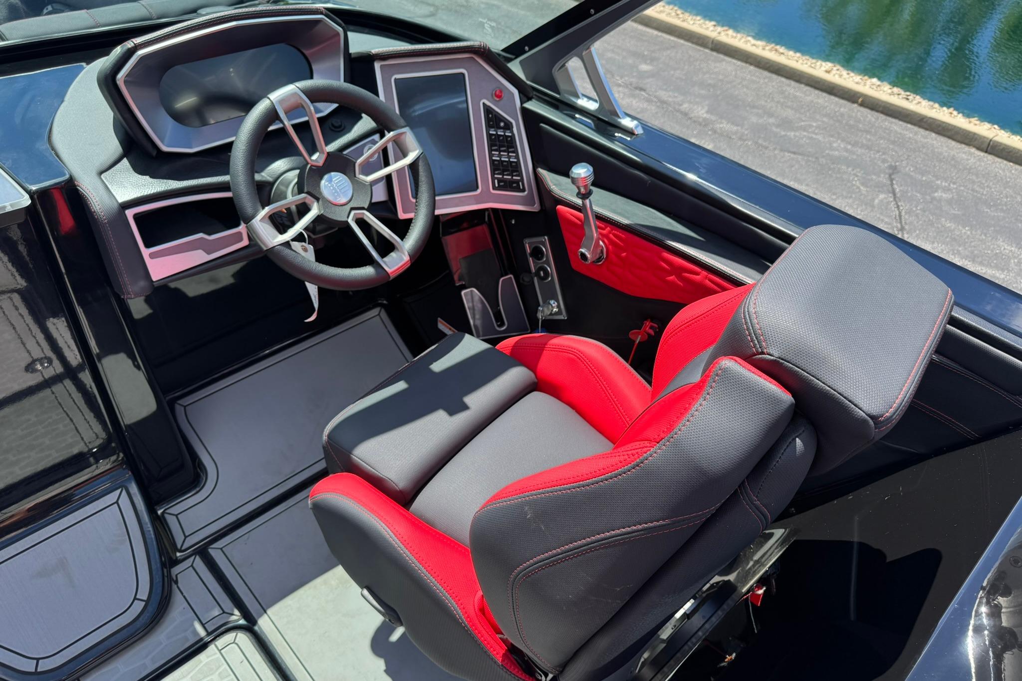 2021 MasterCraft X26 boat cockpit with modern steering wheel and red-black seating.