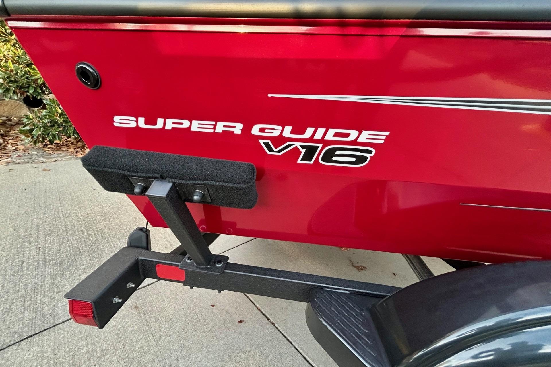 Red 2026 Tracker Super Guide V-16 SC boat on trailer, side view.