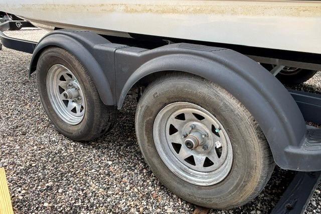 Trailer wheels of a 2021 Chaparral 21 SSi boat on gravel surface.