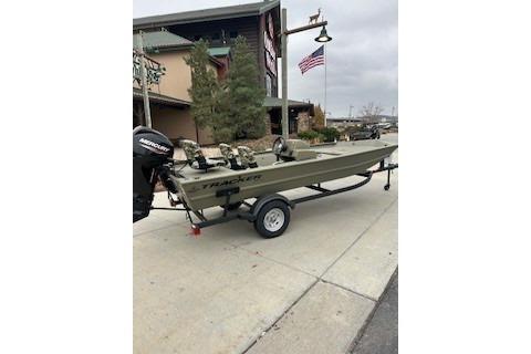 2026 Tracker Grizzly 1754 SC boat on trailer, parked outdoors near a building and American flag.