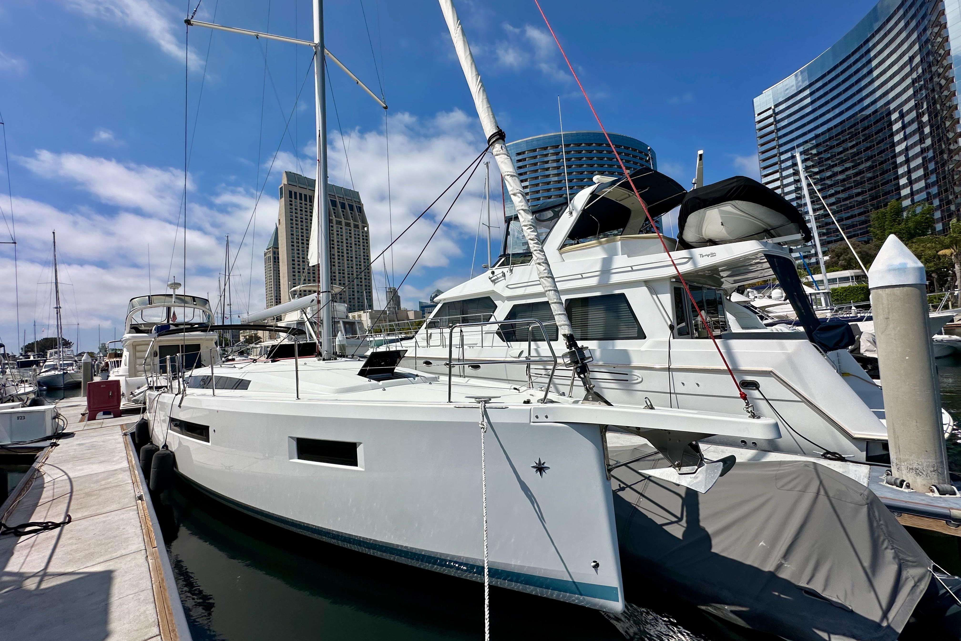 2024 Jeanneau Sun Odyssey 410 sailboat docked in a marina with modern buildings in the background.
