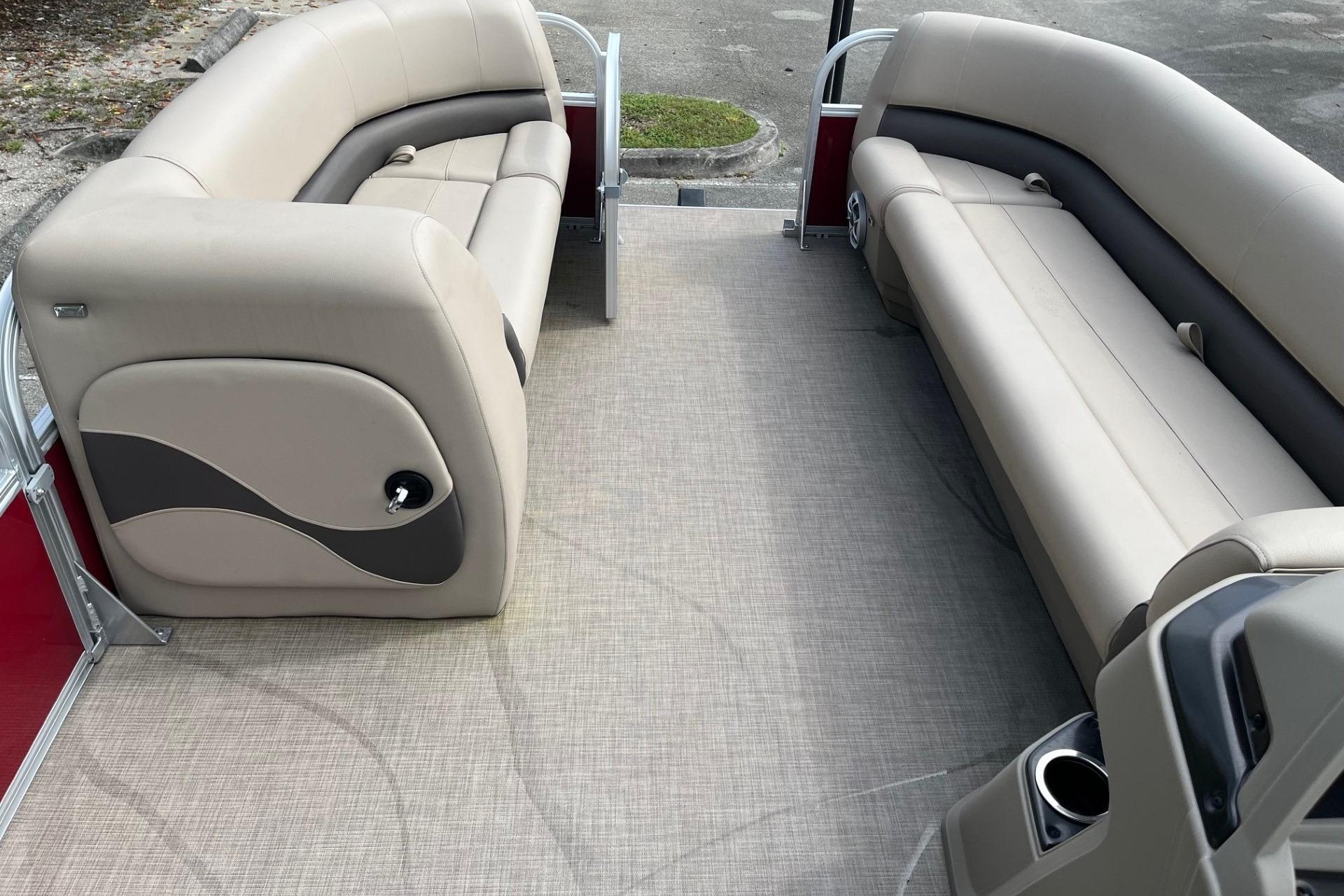 2025 Sun Tracker Party Barge 18 DLX interior with beige seating and carpeted floor.
