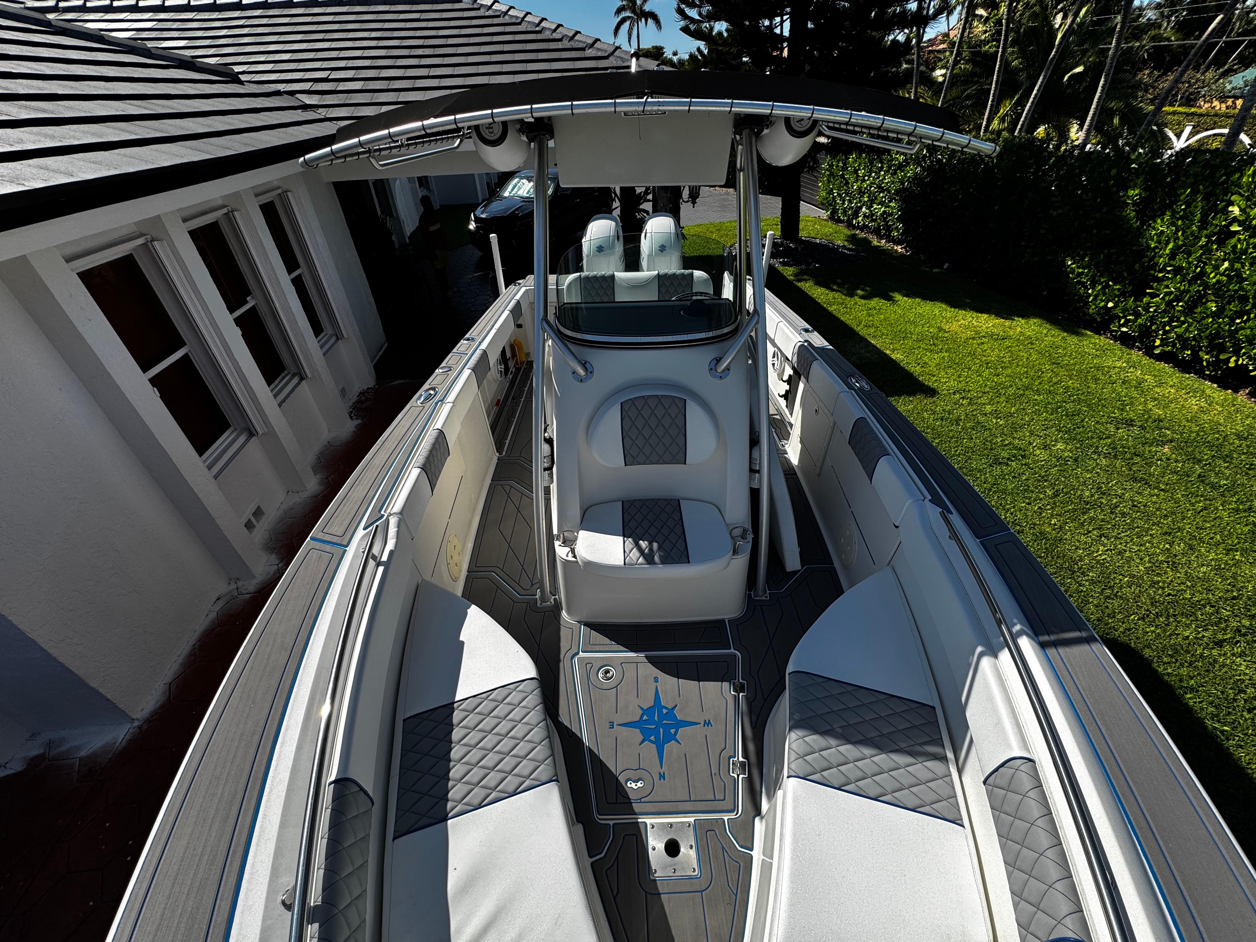 2004 Robalo R 260 boat with sleek interior and T-top, parked beside a house.