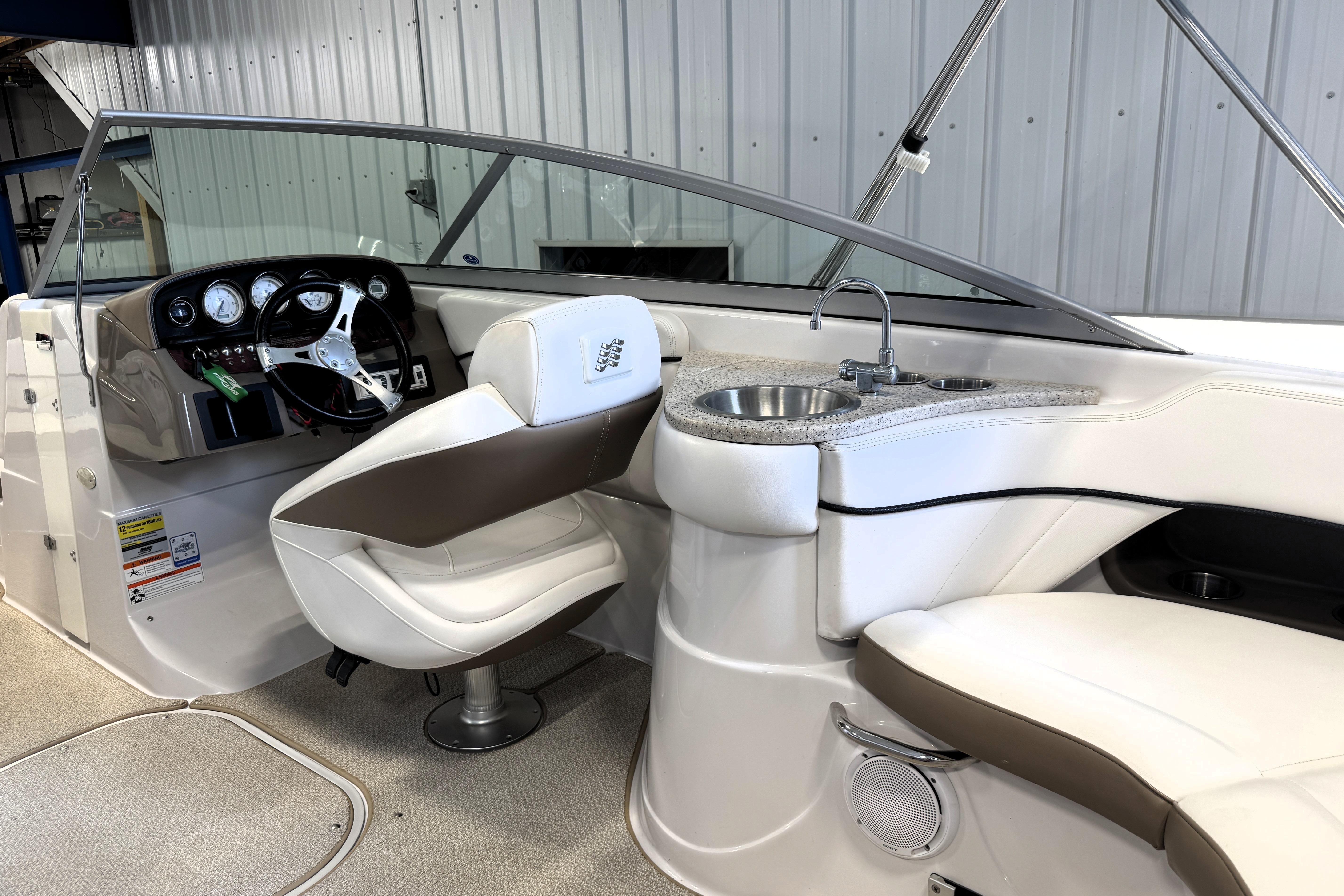 2008 Four Winns H240 boat interior with steering wheel, seating, and sink.
