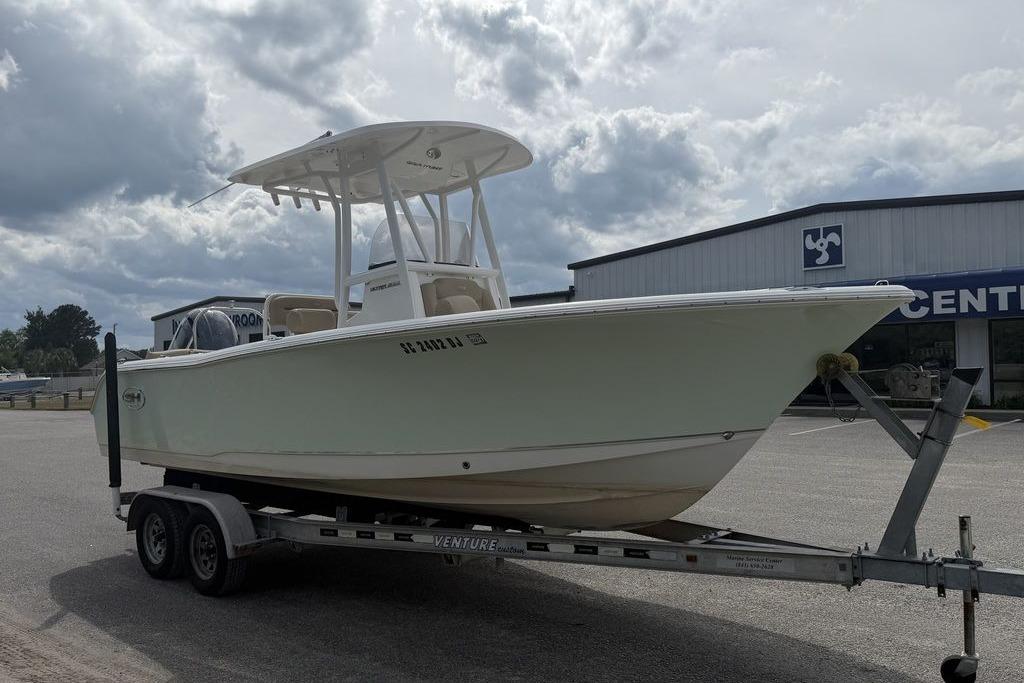 2018 Sea Hunt Ultra 225 boat on trailer, parked outside a showroom under cloudy skies.
