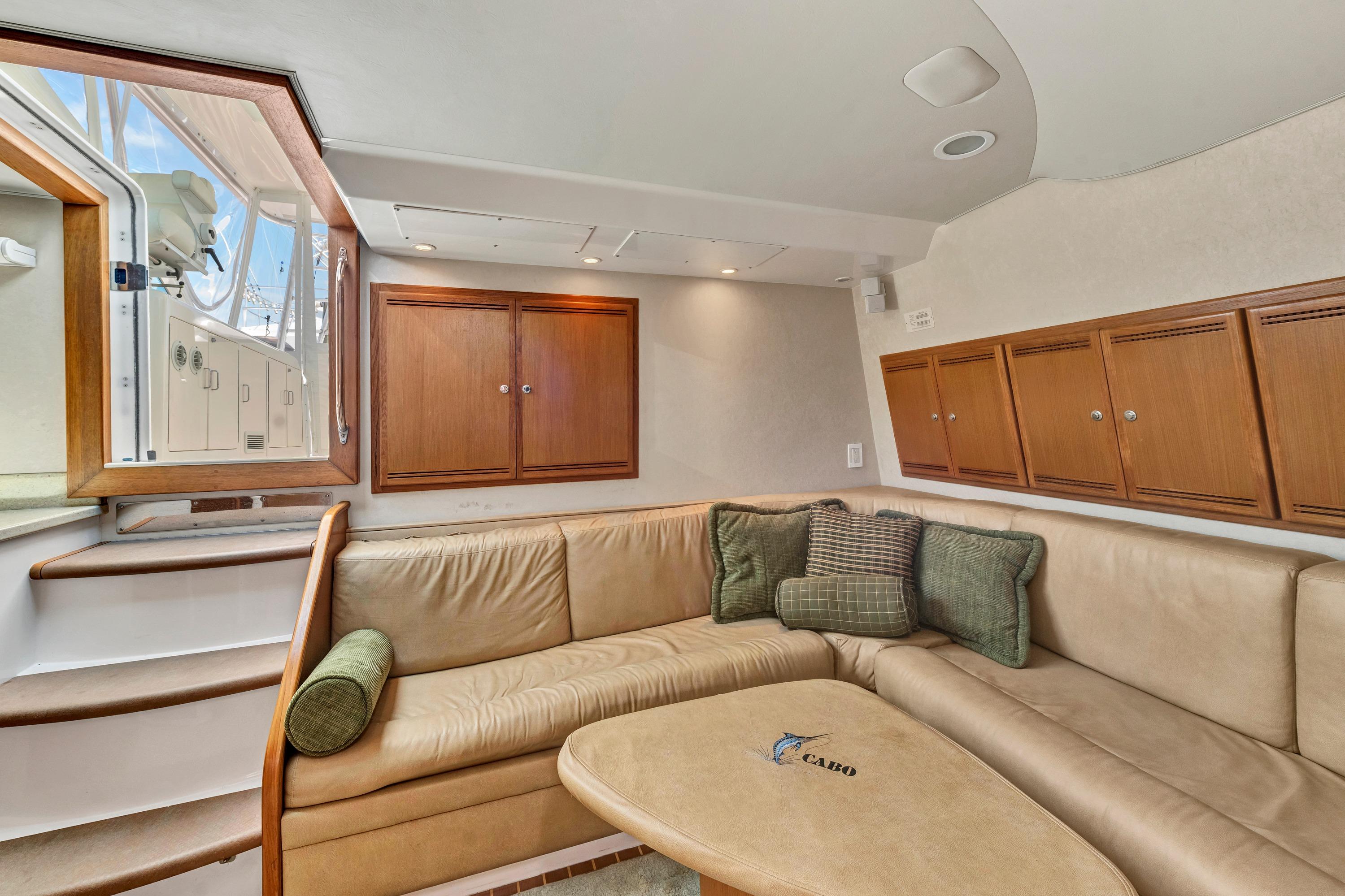 Luxurious interior of 2010 Cabo 45 Express yacht with beige seating and wooden cabinets.
