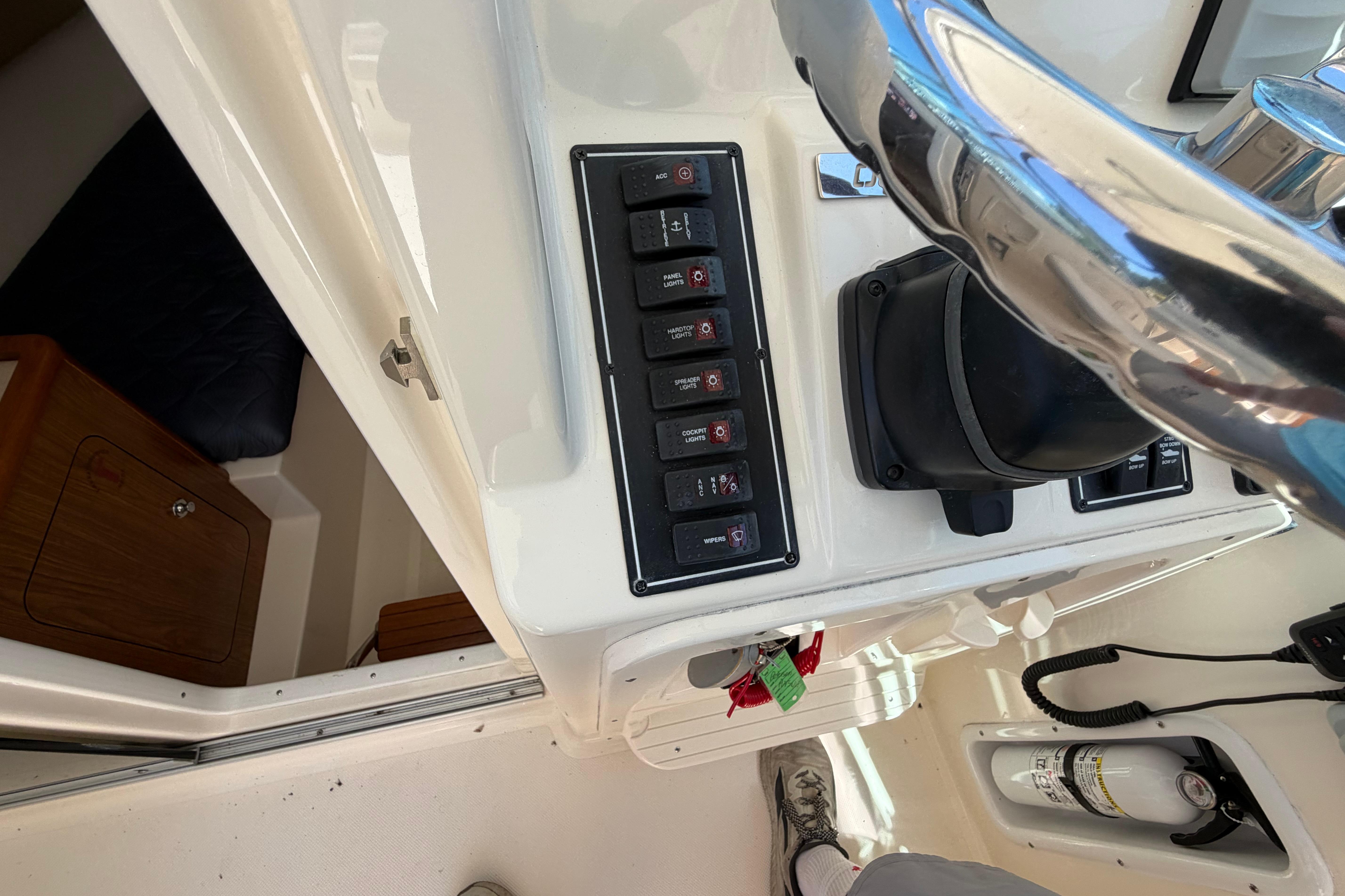 Control panel of a 2010 Pursuit OS 255 Offshore boat with switches and steering wheel.