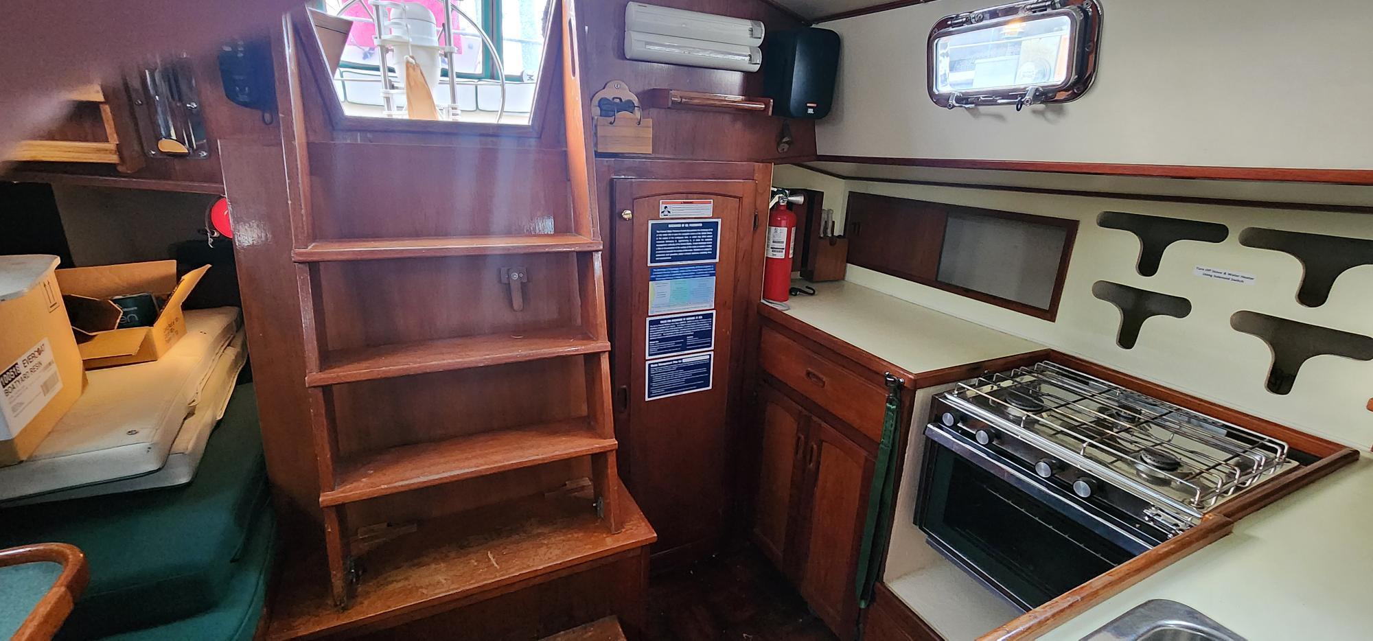 1984 Clearwater Cutter interior with wooden stairs, compact kitchen, and storage cabinets.