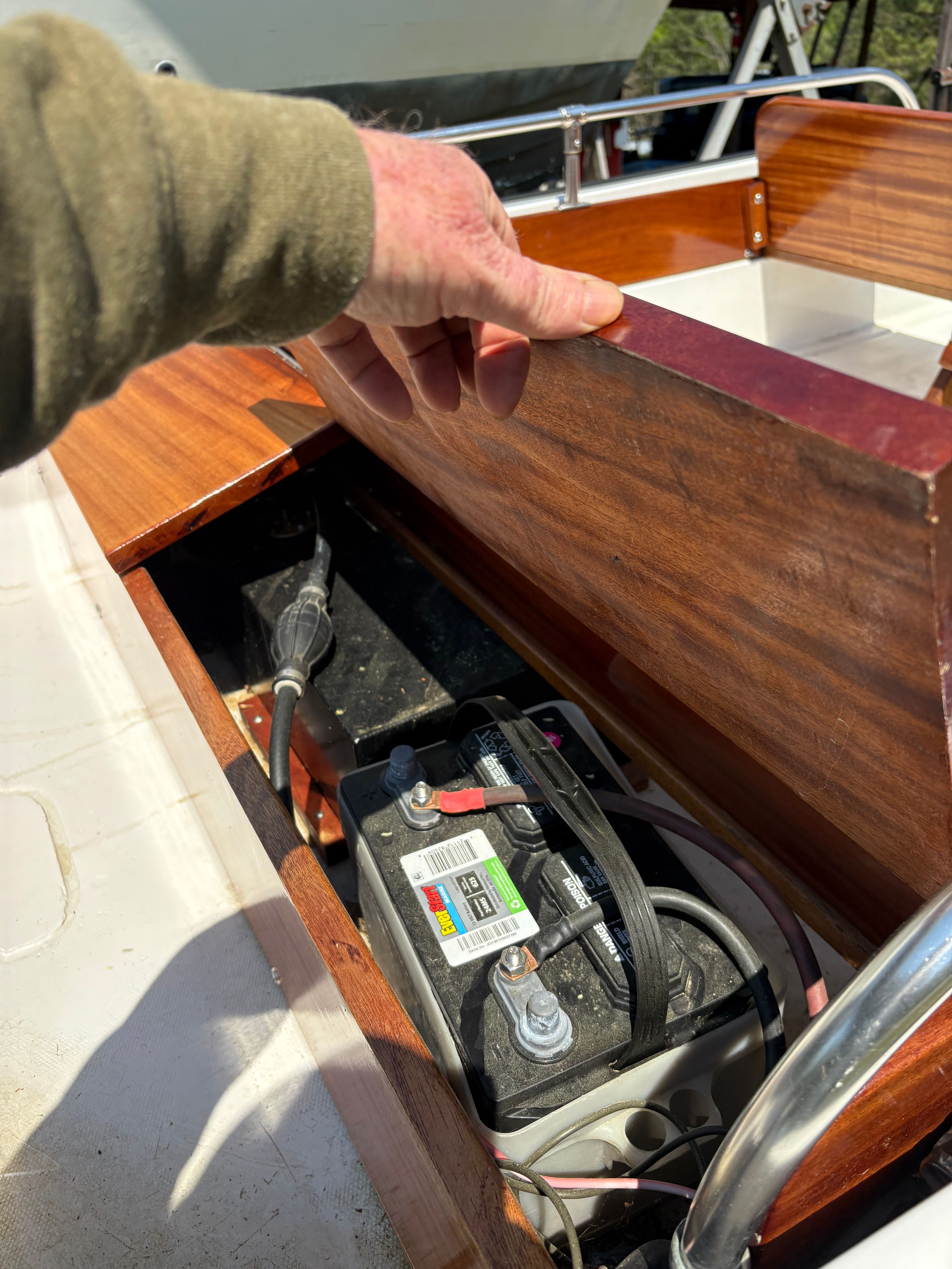 Battery compartment of a 1977 Boston Whaler 13 boat with wooden cover.