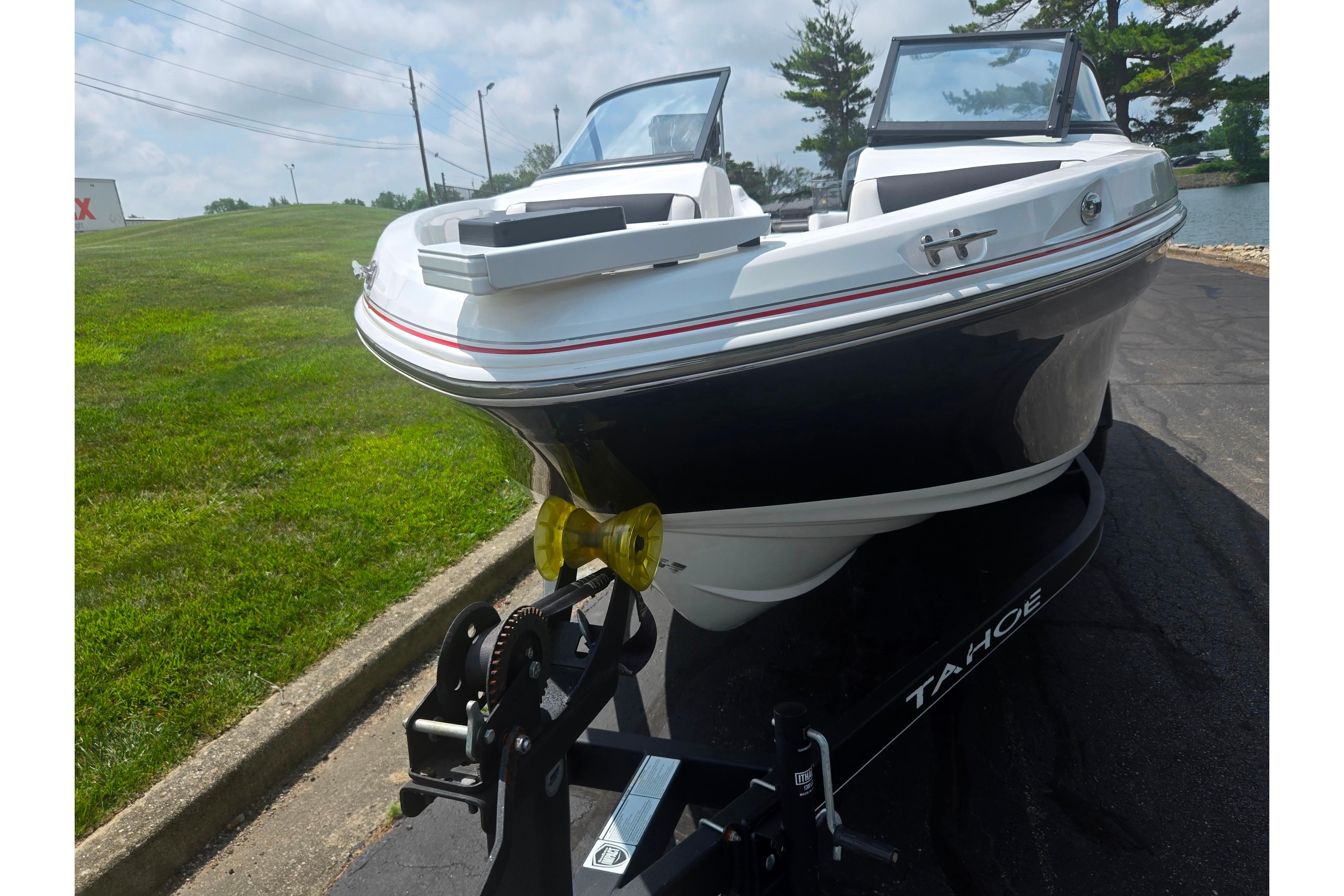 2023 Tahoe 200 S boat on trailer, parked on asphalt near grassy area.