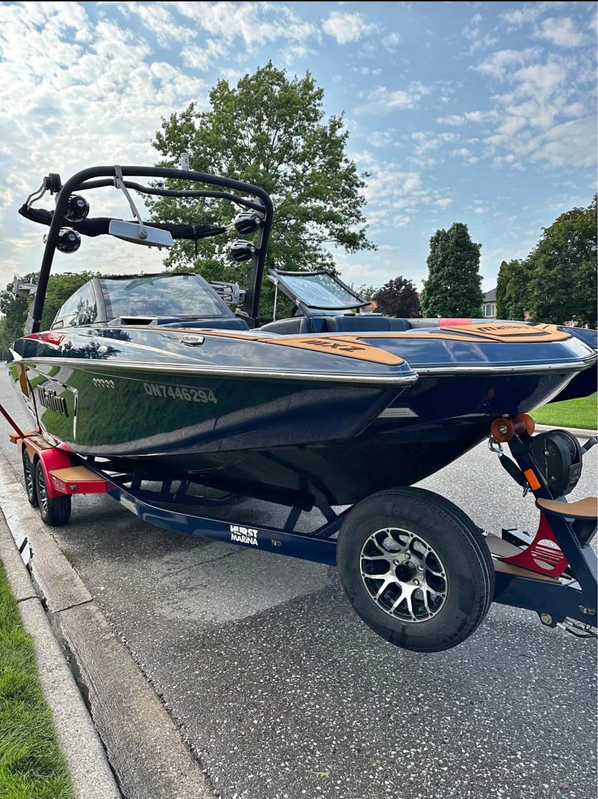 2021 Malibu Wakesetter 24 MXZ boat on trailer, parked on a suburban street.