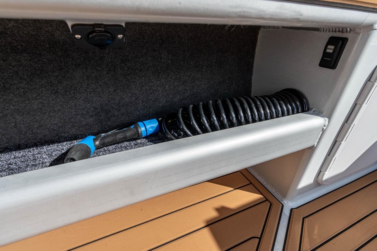 Storage compartment in 2025 Makaira Gen 3 36 boat with coiled hose and switch.