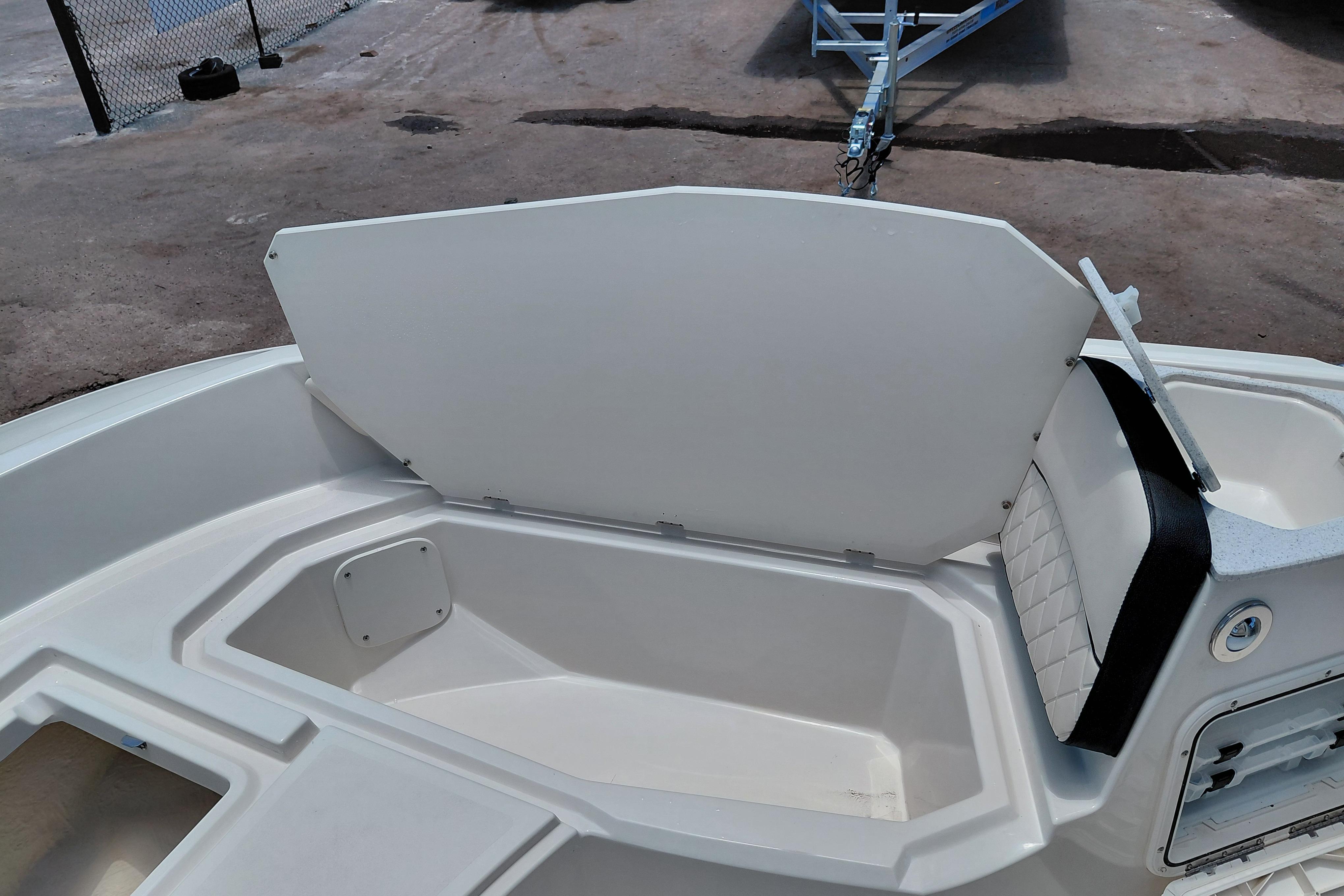 Open storage compartment on 2023 Stingray 206 CC boat, featuring white interior and seating.